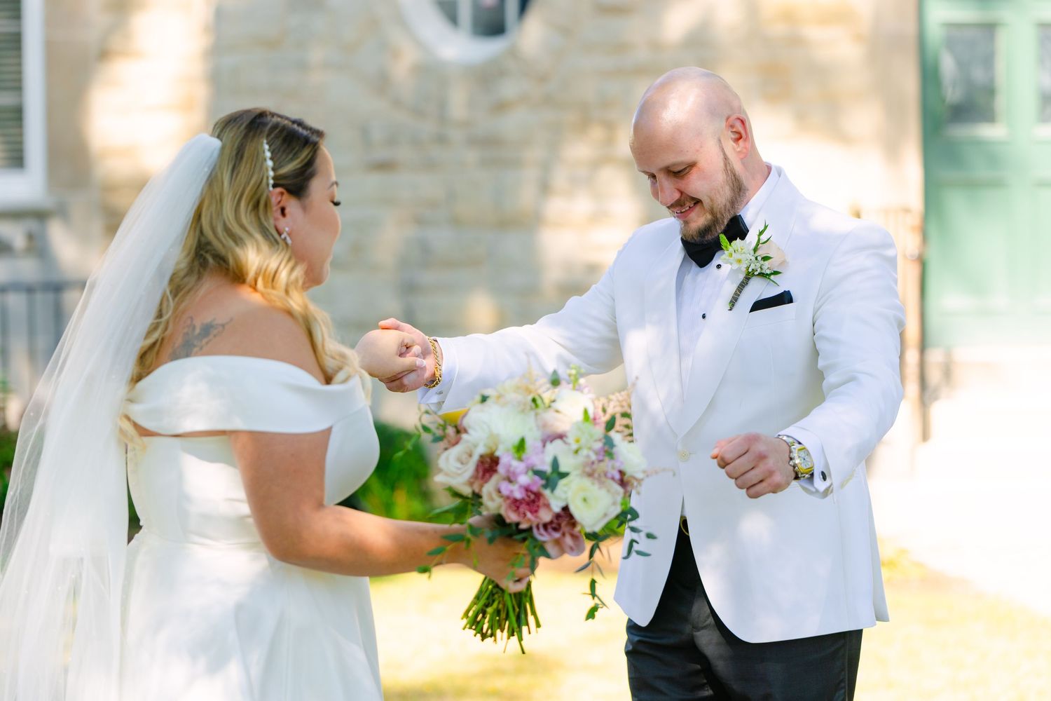 Beautiful outdoor first look wedding photo with couple standing in green garden setting.