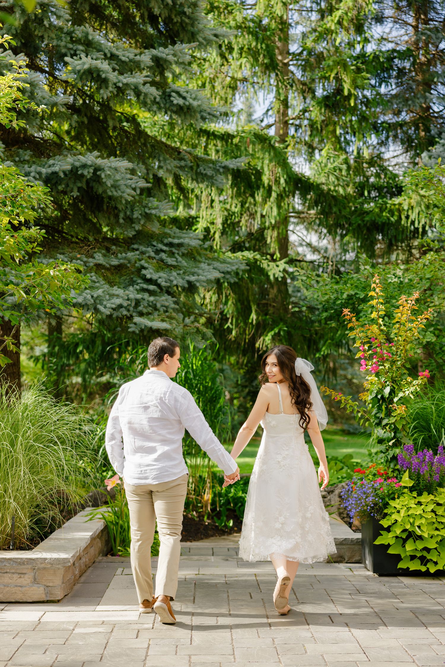 Candid shot of a couple dancing and twirling on a garden pathway during their wedding celebration.