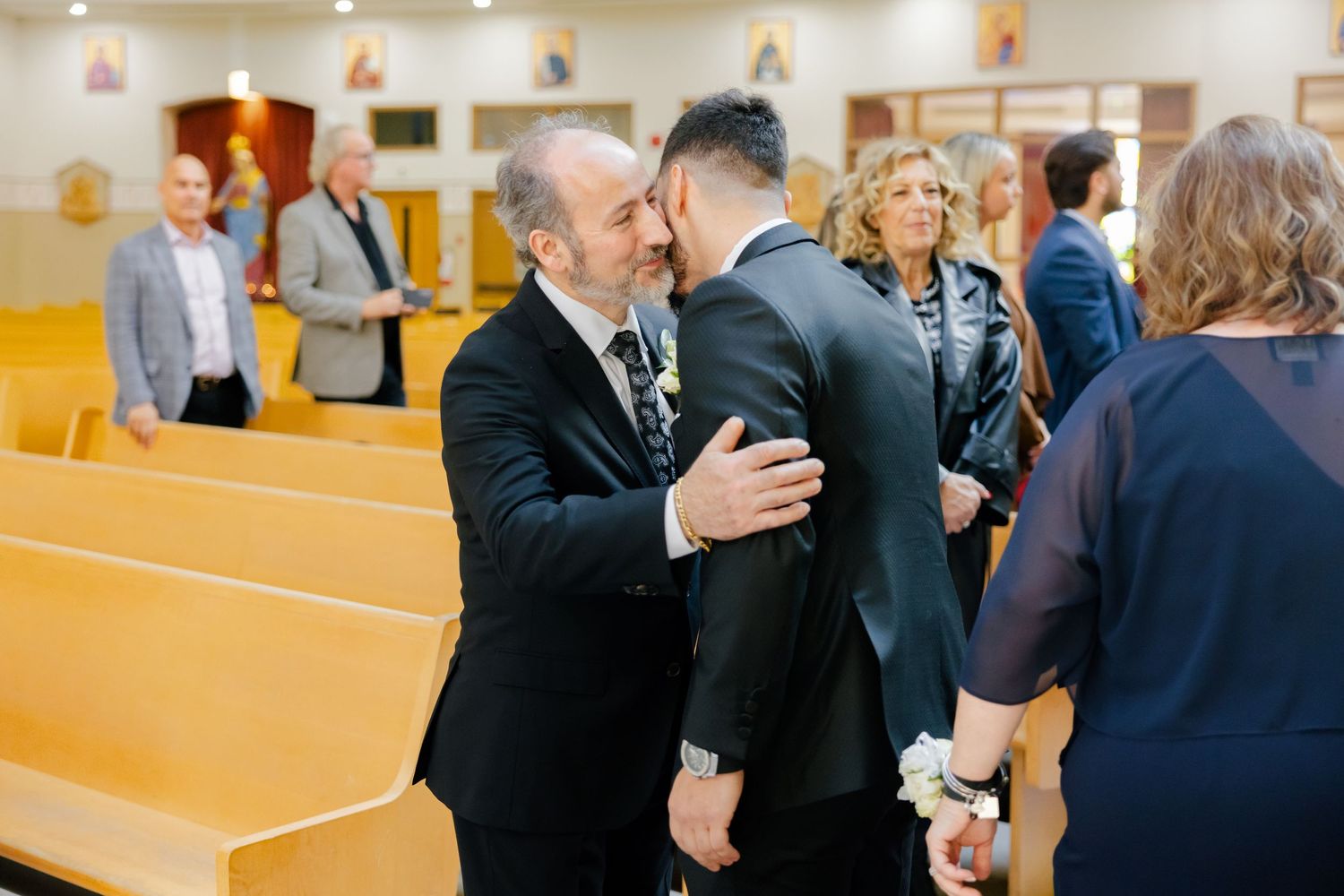 Two people embrace during an emotional moment at a church ceremony.