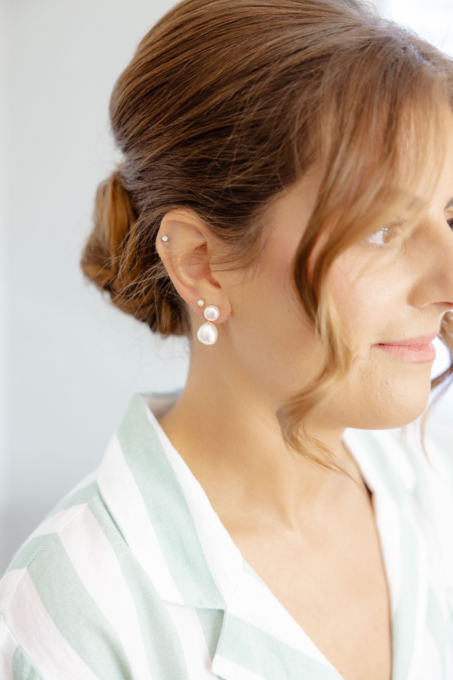 Close-up shot of a pearl earring and striped loungewear in soft lighting.