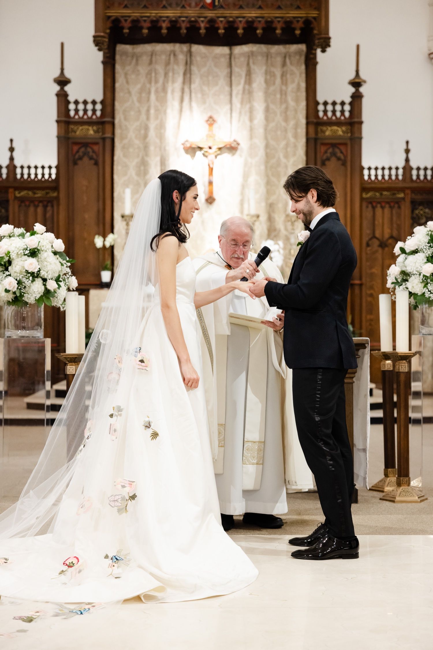 Traditional church wedding ceremony with ornate wooden altar details and white floral arrangements.