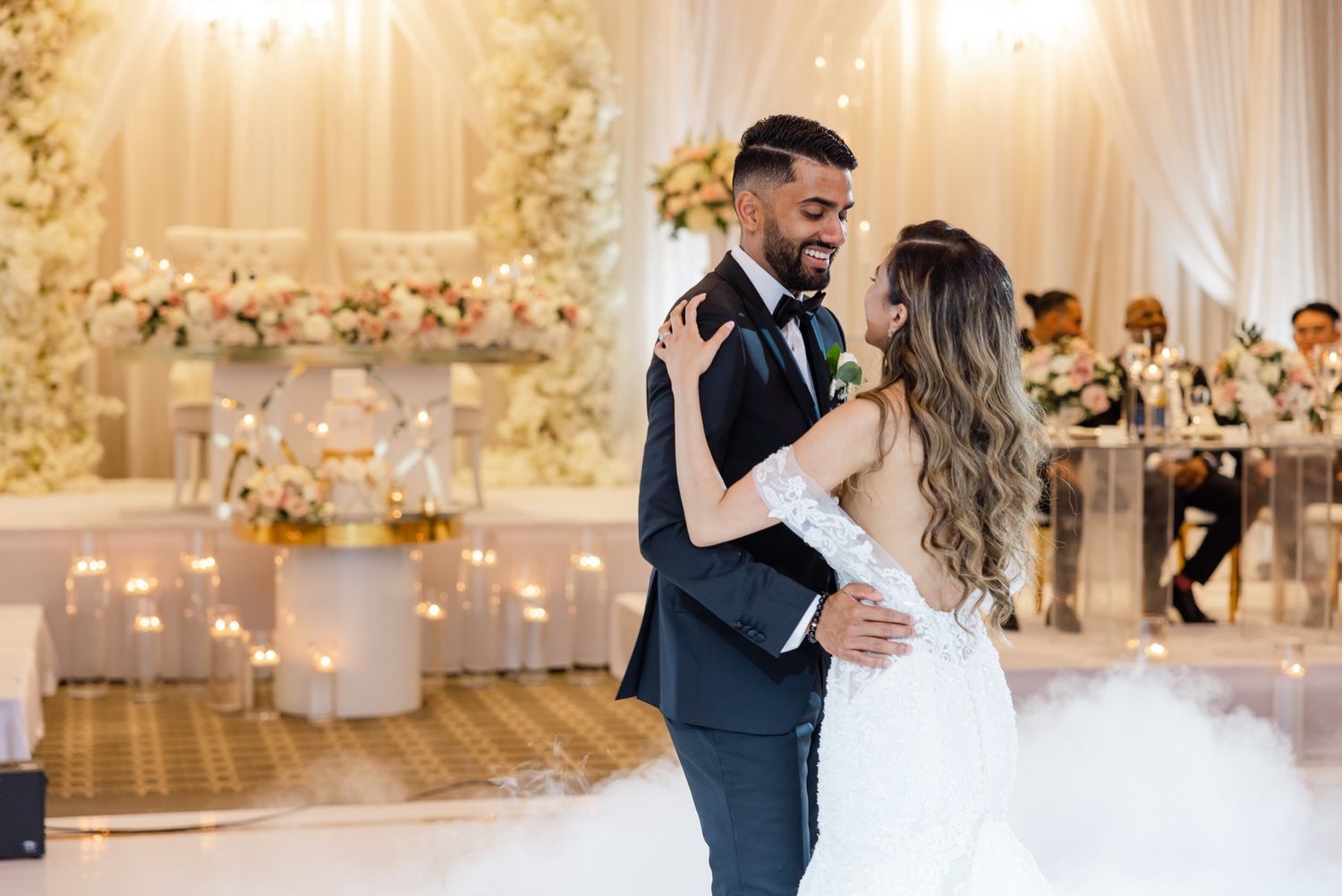 Couple dances in a luxurious ballroom with ornate gold ceiling and floral archway.