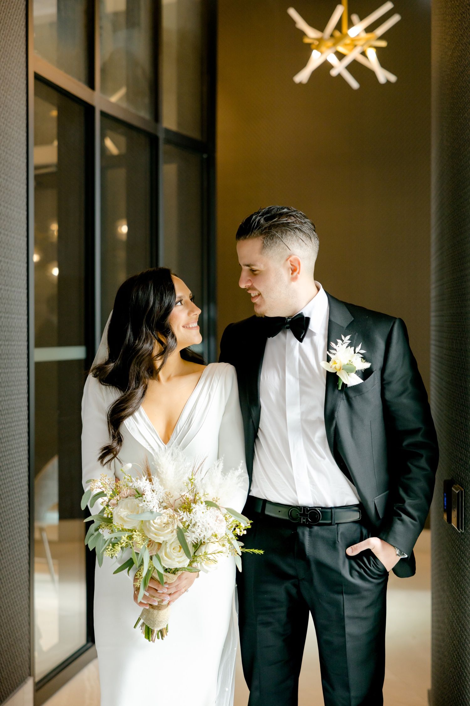 Elegant wedding portrait in modern venue with distinctive lighting and glass wall features.