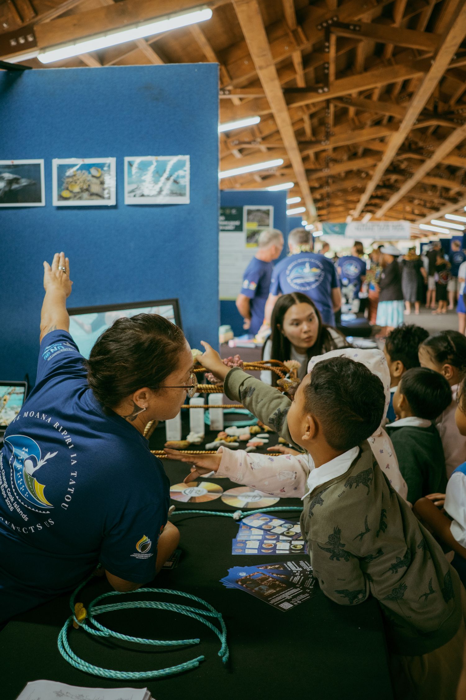 Marine educator engages children at an ocean conservation booth during an indoor educational fair event.