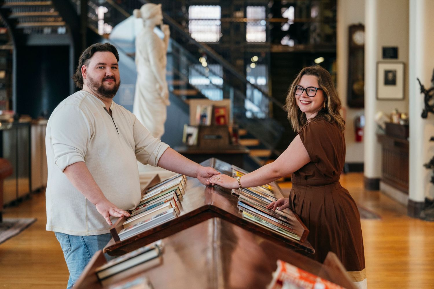 A man and woman smile while browsing vinyl records together in a charming vintage shop filled with art and decor.