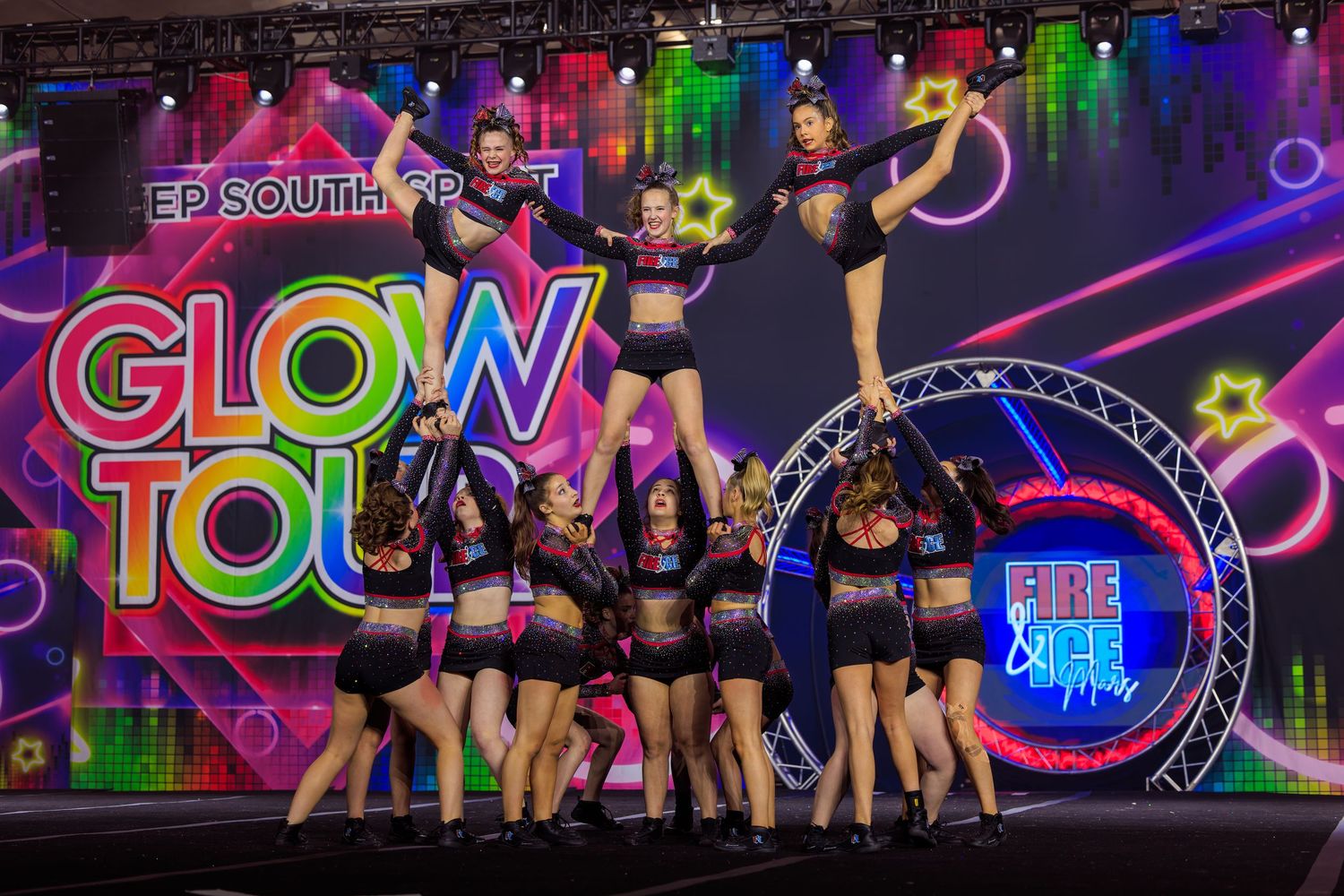 Cheerleading squad performs a stunning stunt pyramid at the colorful Glow Tour competition event.