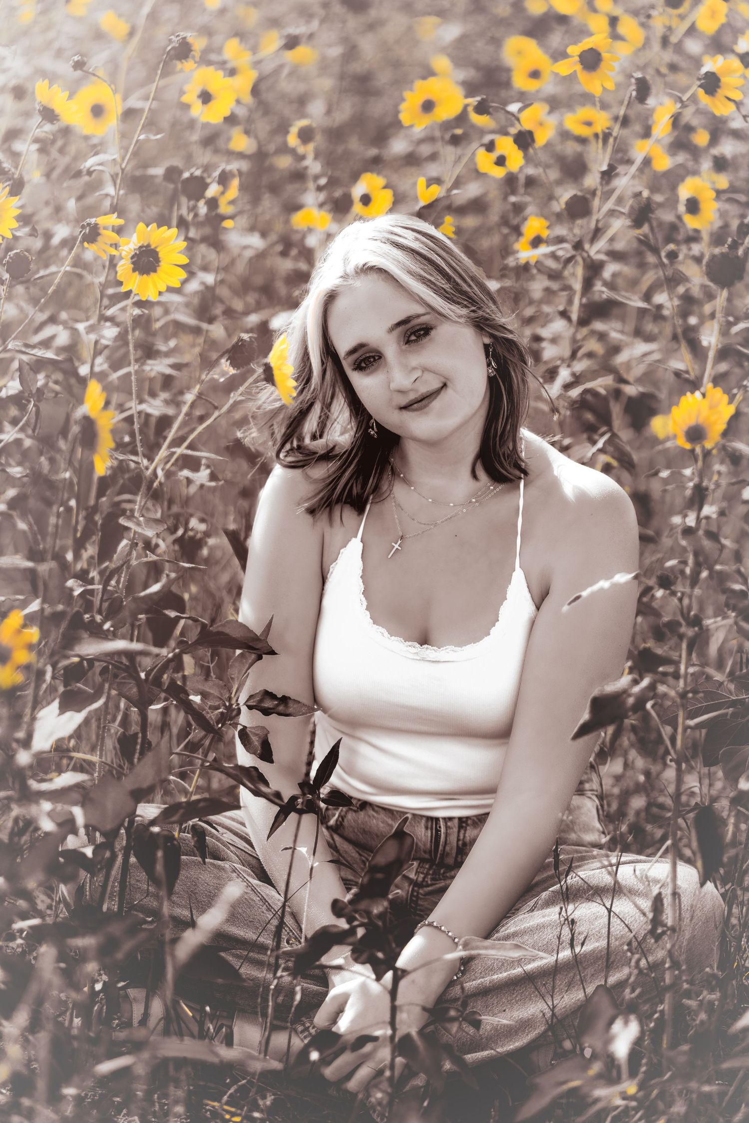 Young woman sitting in a sunflower field wearing white tank top in vintage sepia-toned portrait.