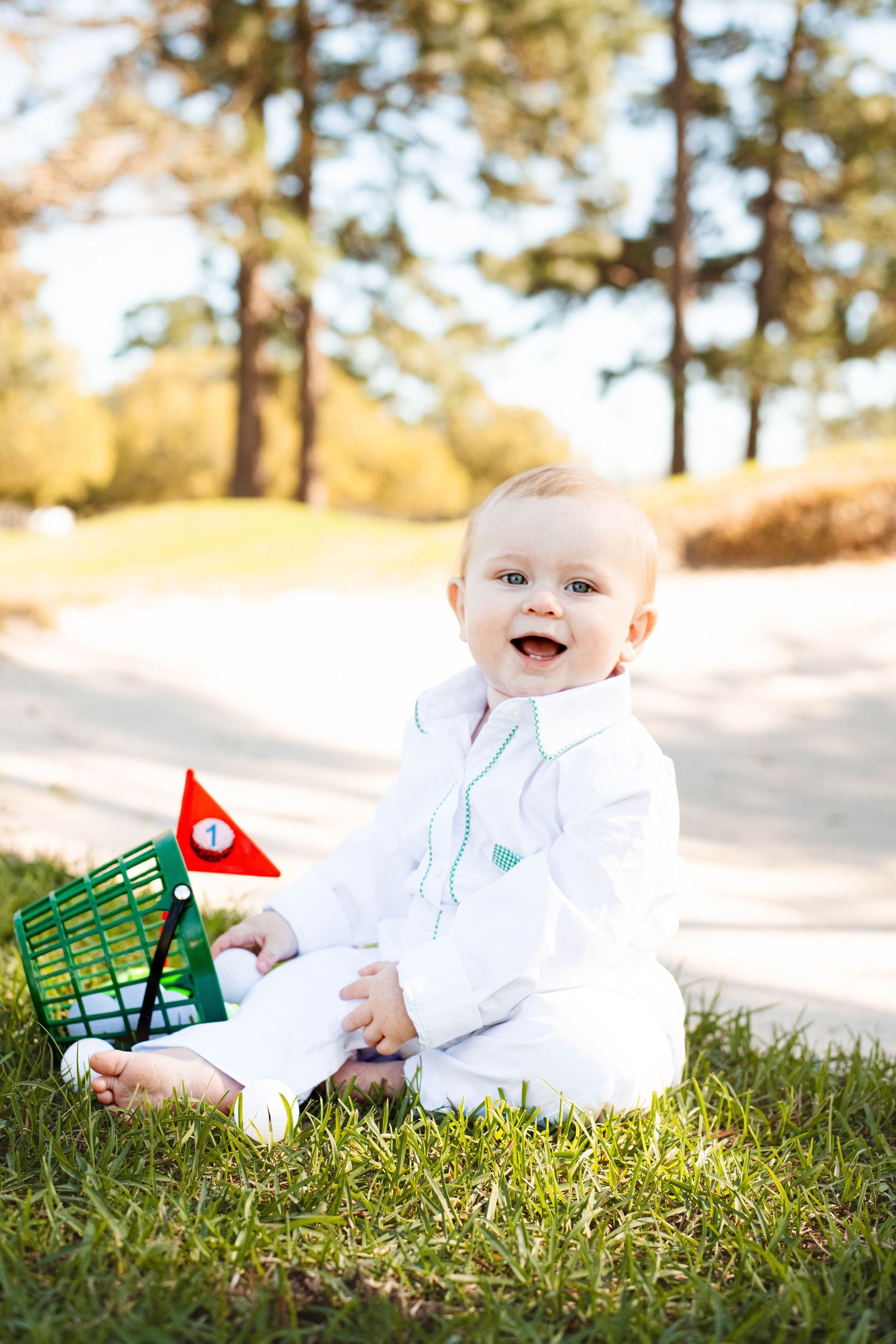 Young boy smiling on a golf course in Hurley, Mississippi during a first birthday session