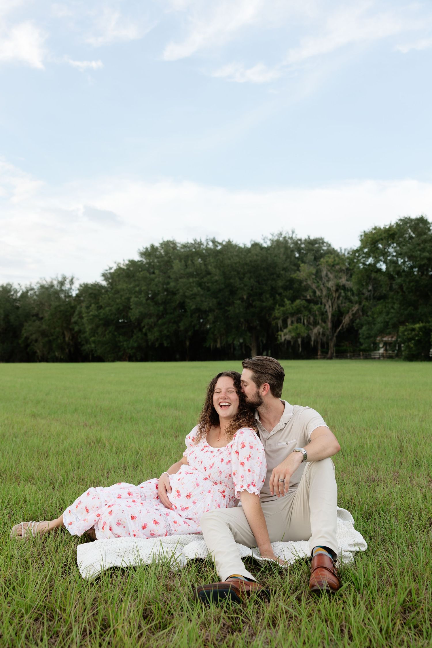 A romantic couple sitting in a grassy Florida field during a golden hour lifestyle photography session.