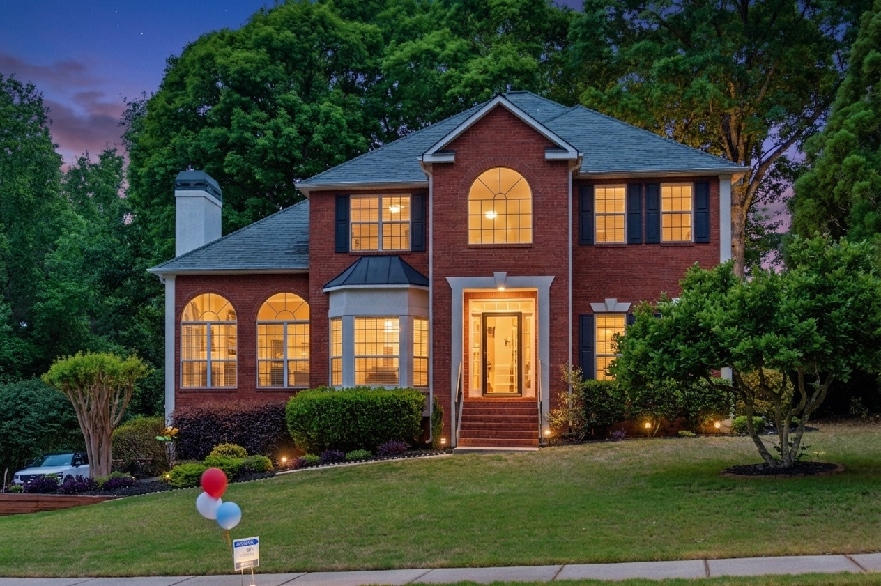 Elegant two-story brick home with arched windows, manicured lawn, and twilight lighting.