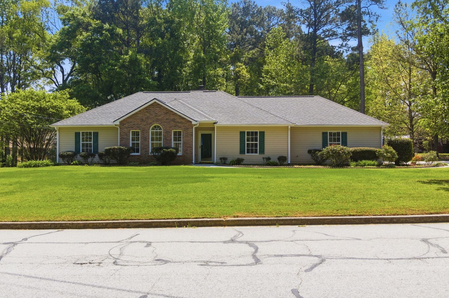 Charming single-story brick ranch home with manicured lawn, mature trees, and classic curb appeal.