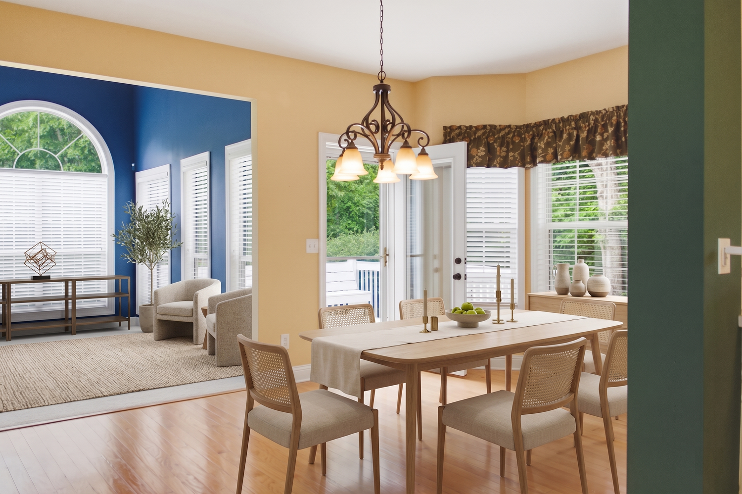Sunny dining room with yellow walls, wood table, chandelier, and blue accent doorway.