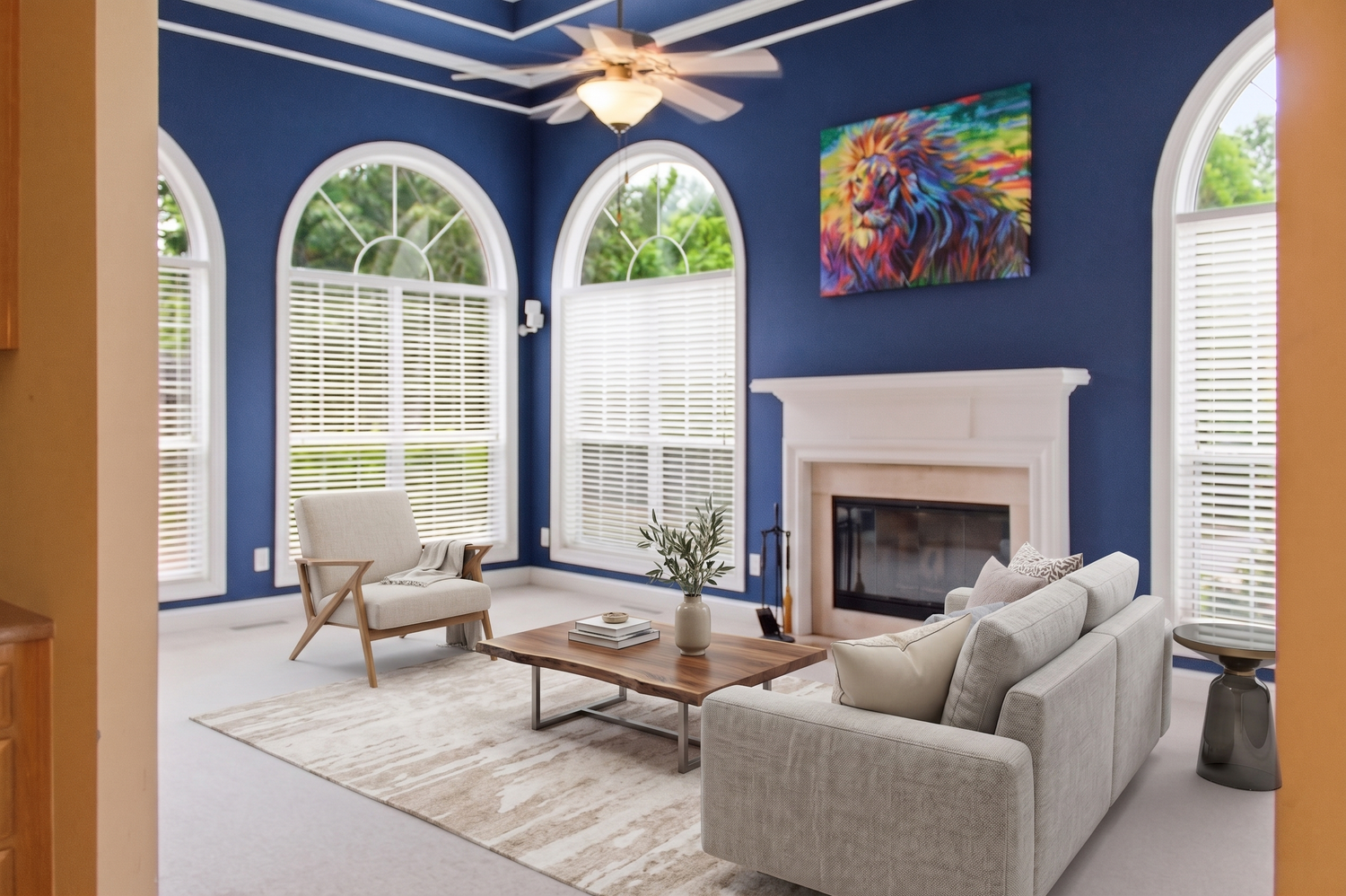 Formal living room with royal blue walls, arched windows, fireplace, and gray sofas.