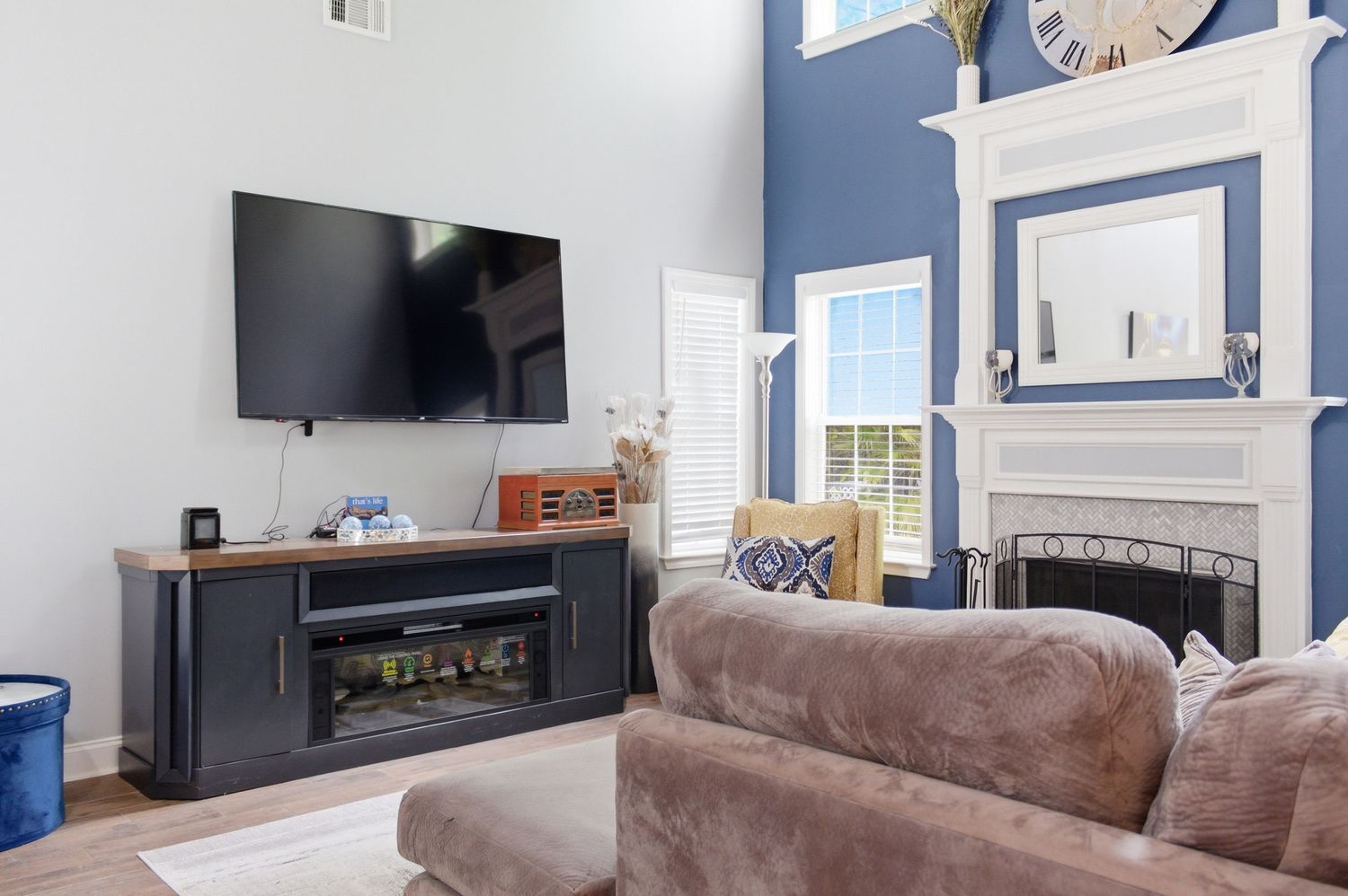 Cozy living room with navy blue fireplace wall, TV console, and brown sectional sofa.