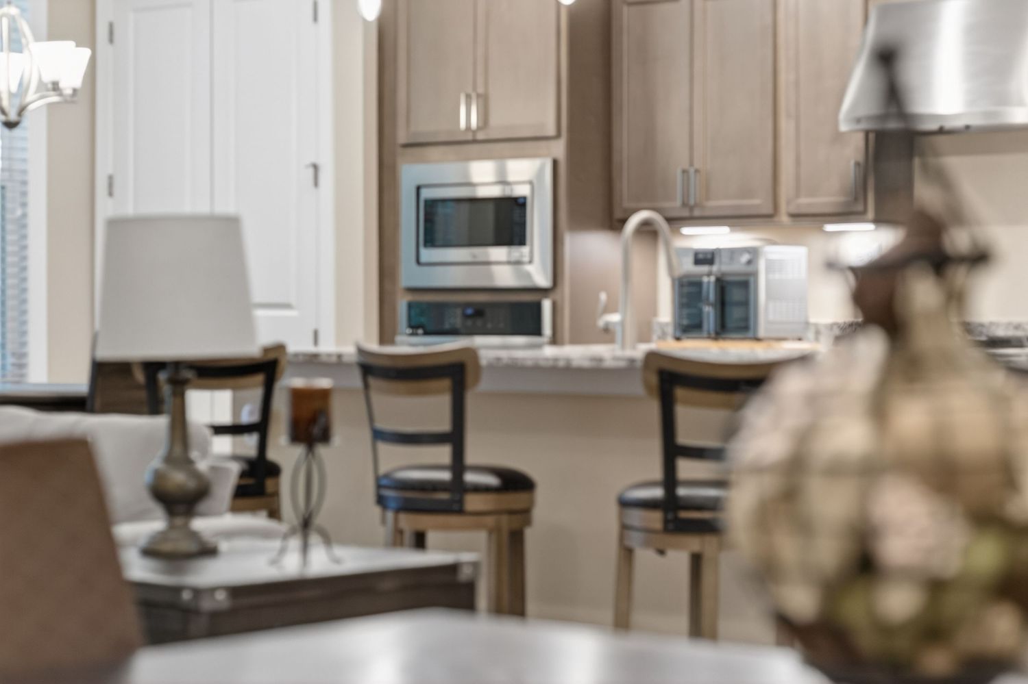 Warm kitchen with taupe cabinets, stainless steel appliances, granite counters, and bar seating area.