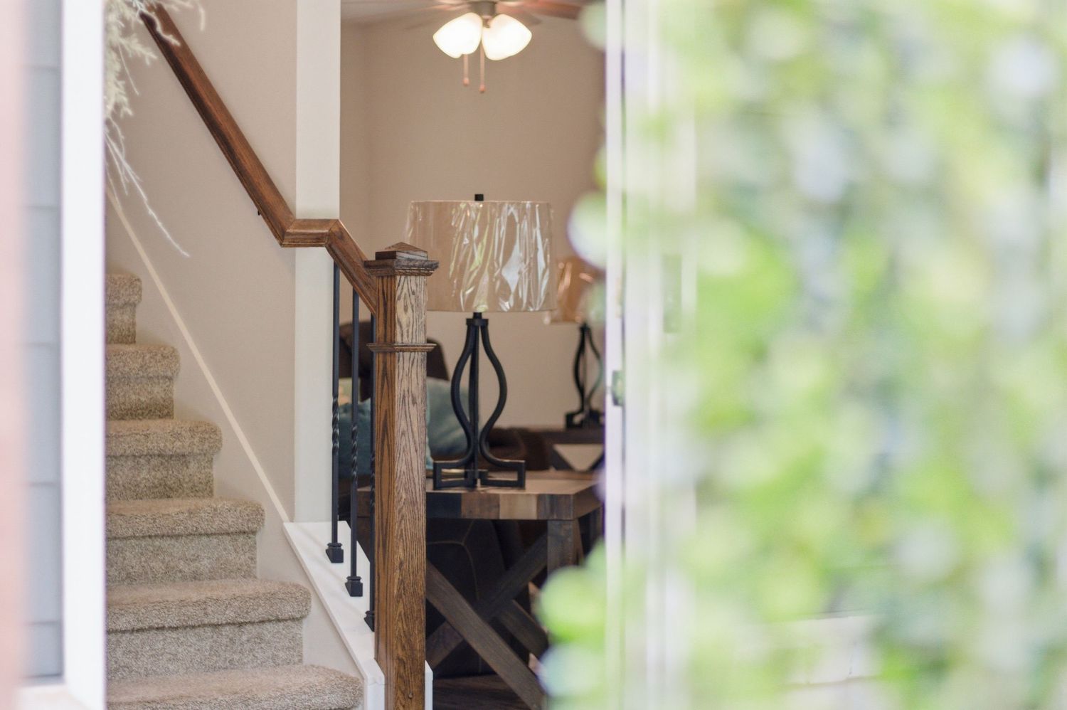 Elegant foyer with carpeted staircase, wood banister, chandelier, and decorative console table.