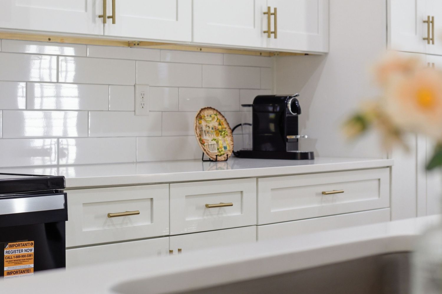 White kitchen with subway tile backsplash, shaker cabinets, gold hardware, and a black espresso machine.