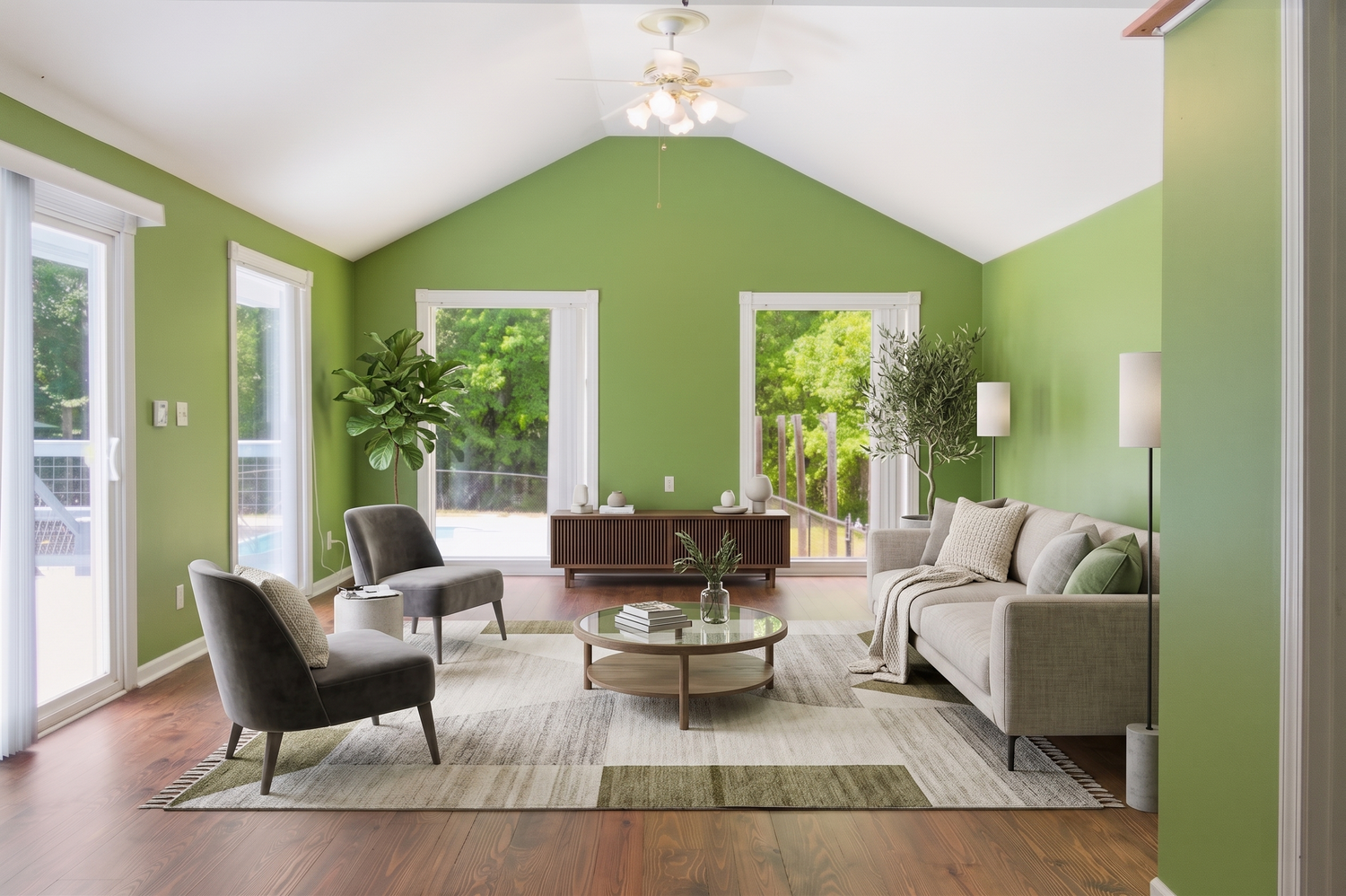 Airy living room with green walls, vaulted ceiling, gray sofa, hardwood floors, and ceiling fan.