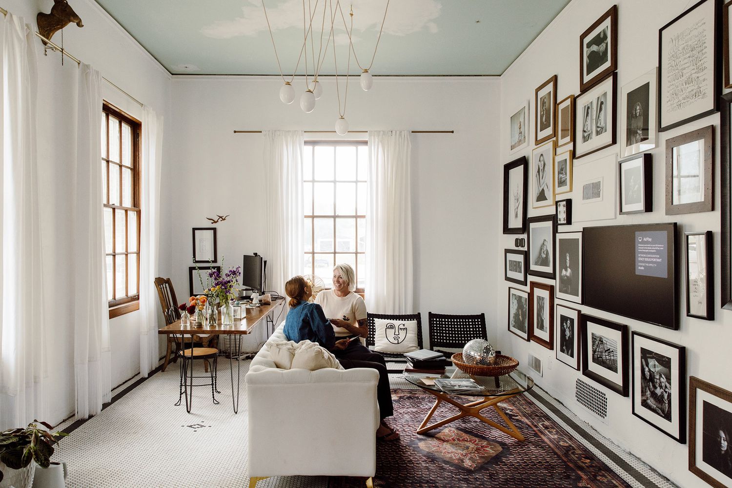 Interior view of a bright gallery space with framed photographs displayed on white walls.