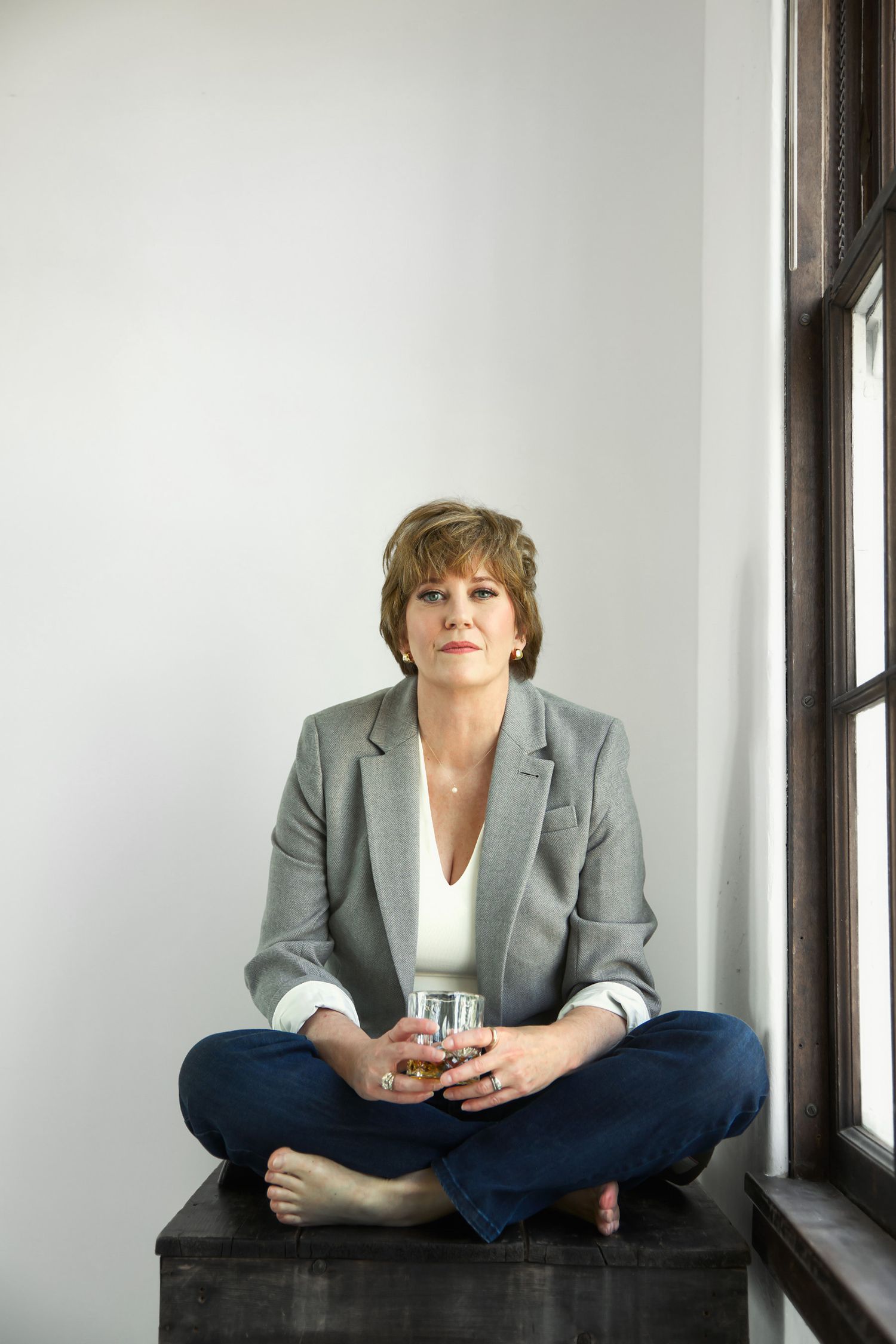 Portrait series of person in casual business attire seated by bright window.