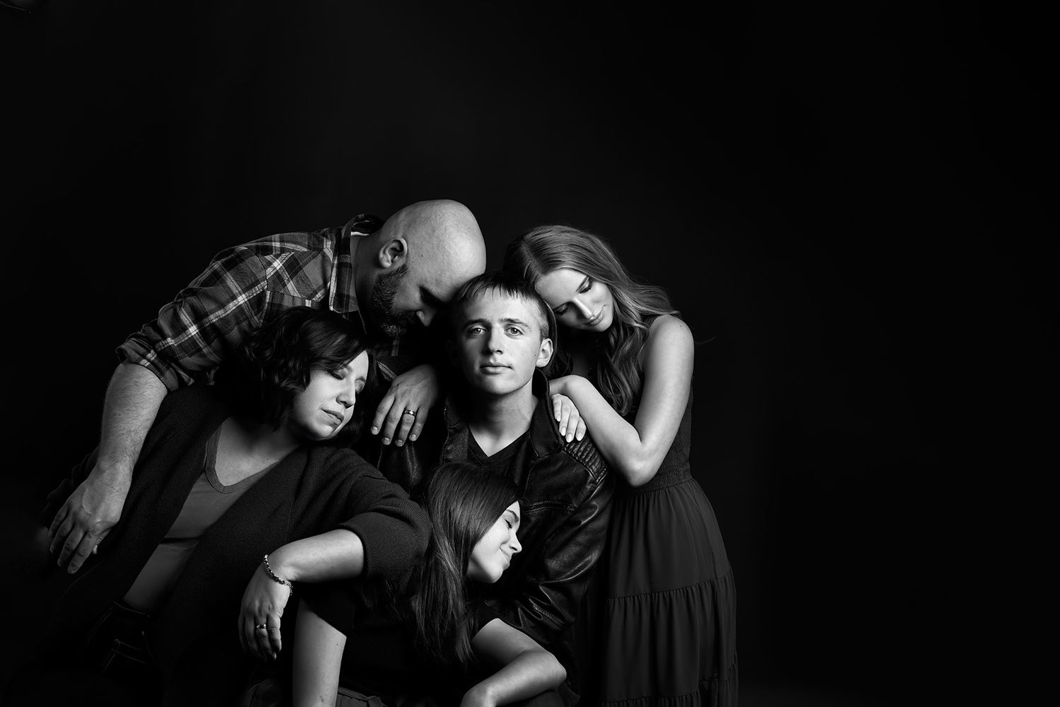 Group portrait in dramatic black and white lighting showing silhouetted figures.
