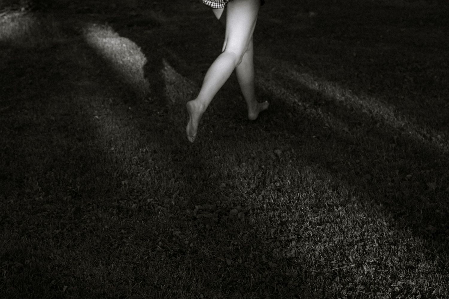 Artistic black and white photo of legs walking on a textured dark surface.