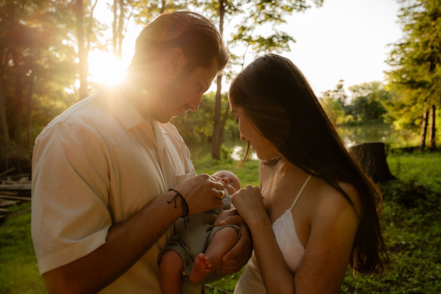 A couple shares an intimate moment in a park at sunset with golden sunlight streaming through the trees.
