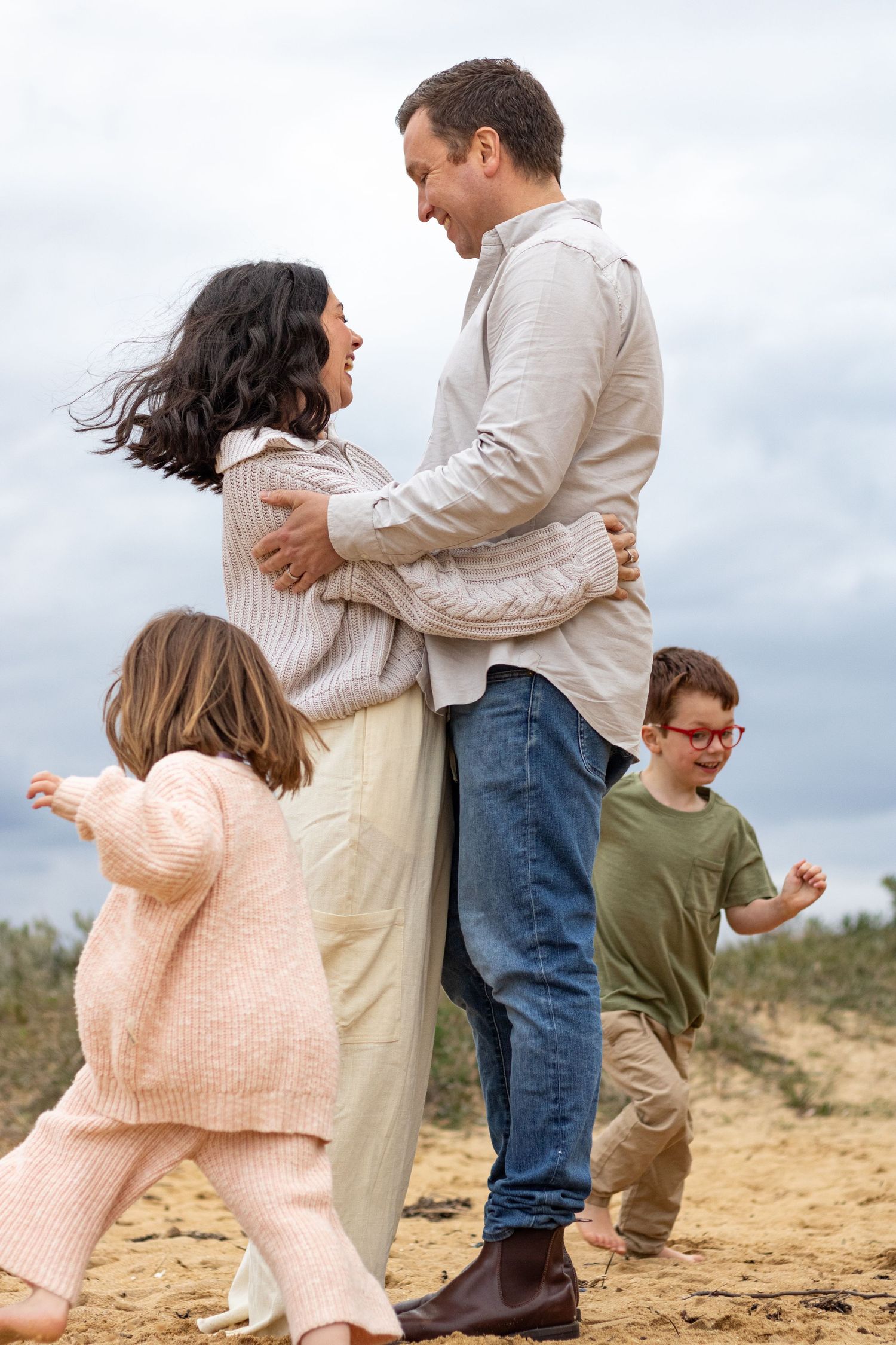 A playful sequence shows a couple dancing together on sandy ground while someone watches in the background.