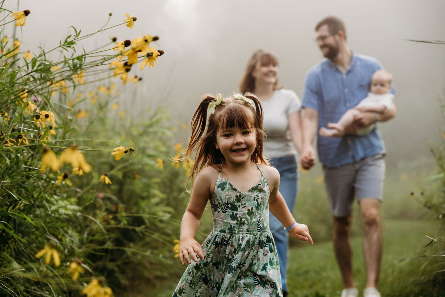 A family enjoys a playful summer moment together in a wildflower meadow filled with yellow blooms at sunset.