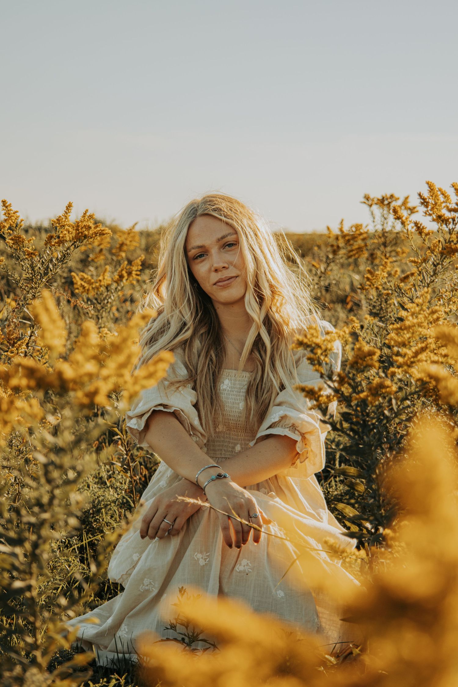Ethereal golden hour portraits in a field of yellow flowers with warm sunlight filtering through the foliage.