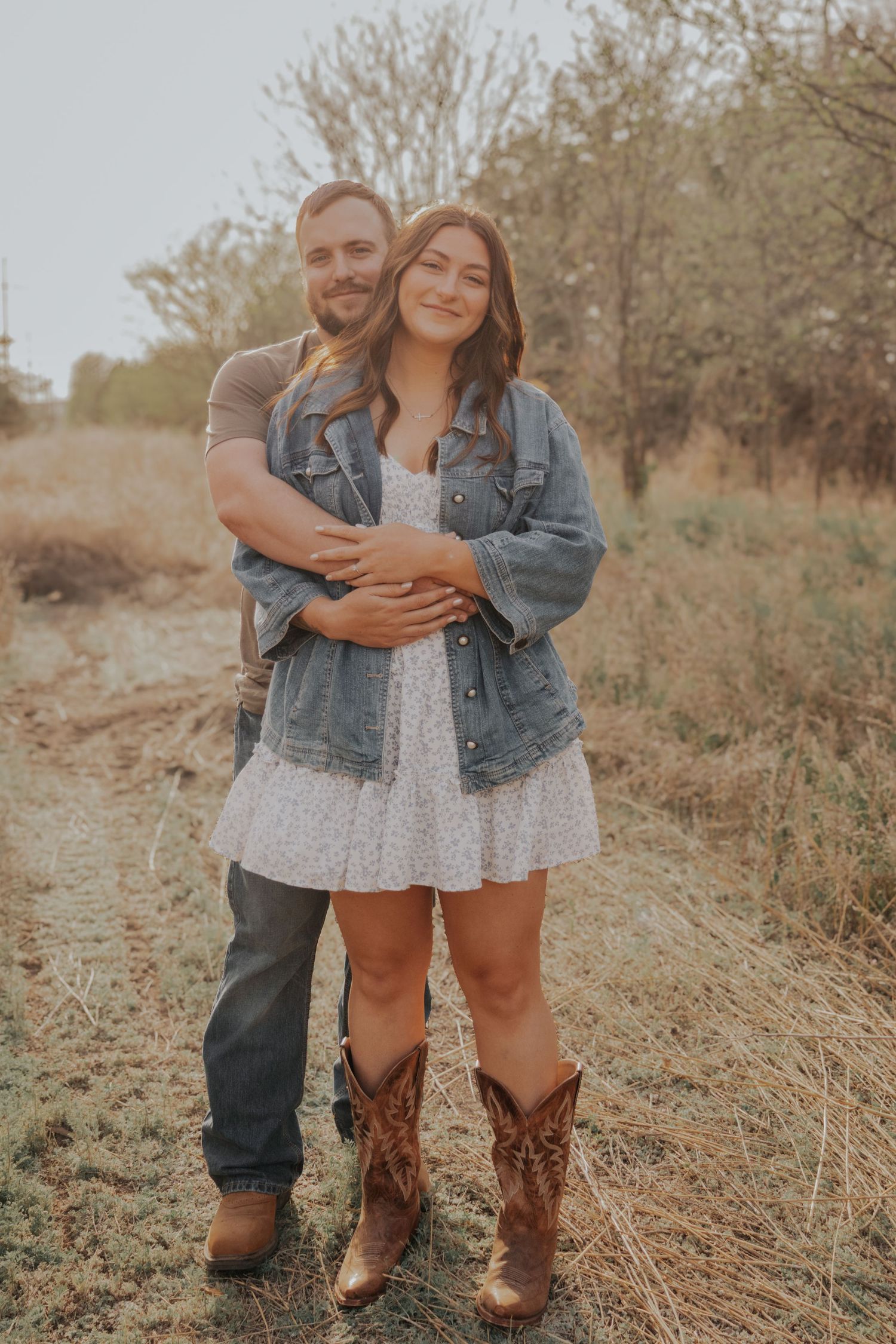 A couple in rustic attire shares intimate embraces in a golden field during sunset.