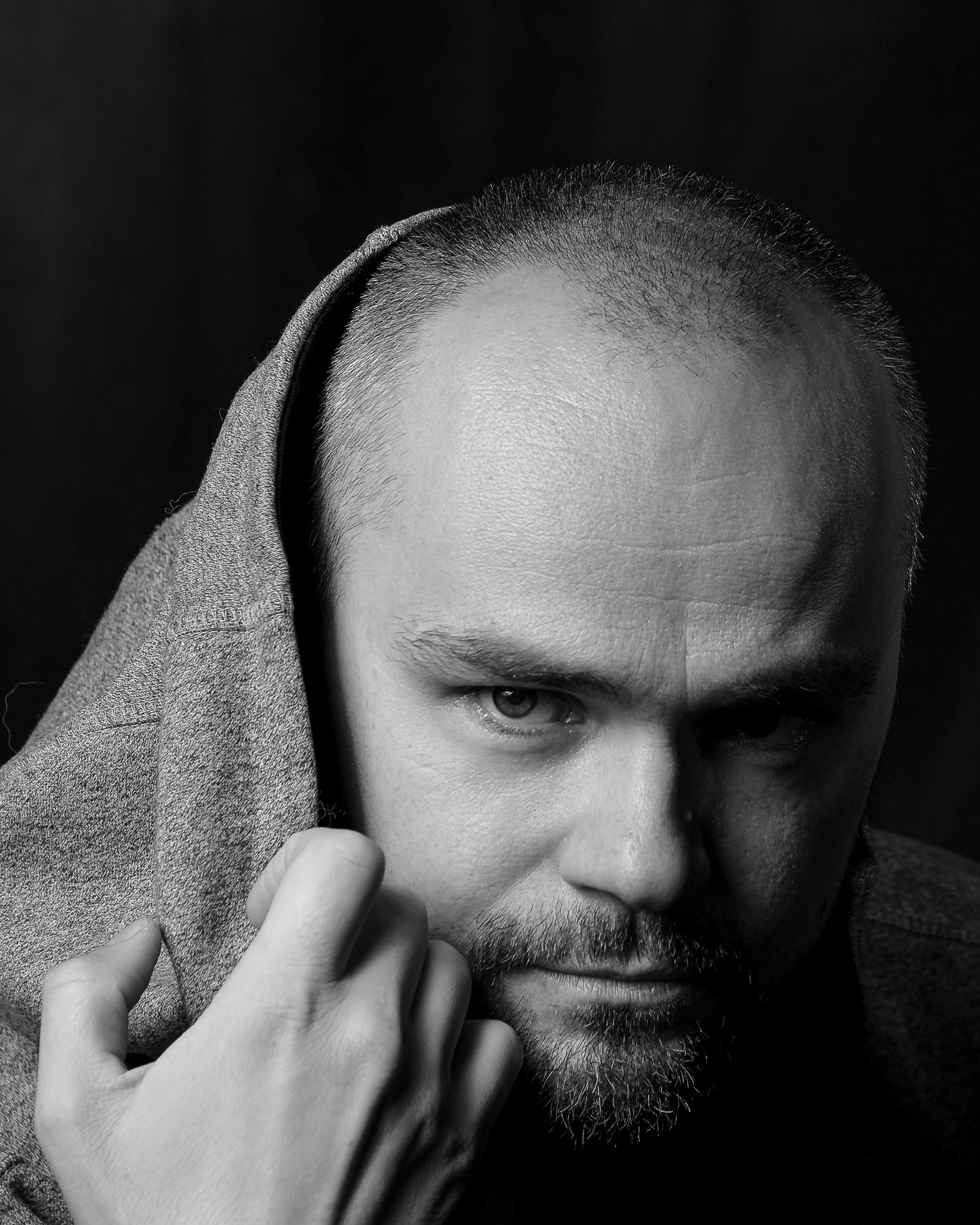 Editorial photographer's portrait: strong monochrome profile study, hands and grey fabric textured, professional studio, high-end feel.