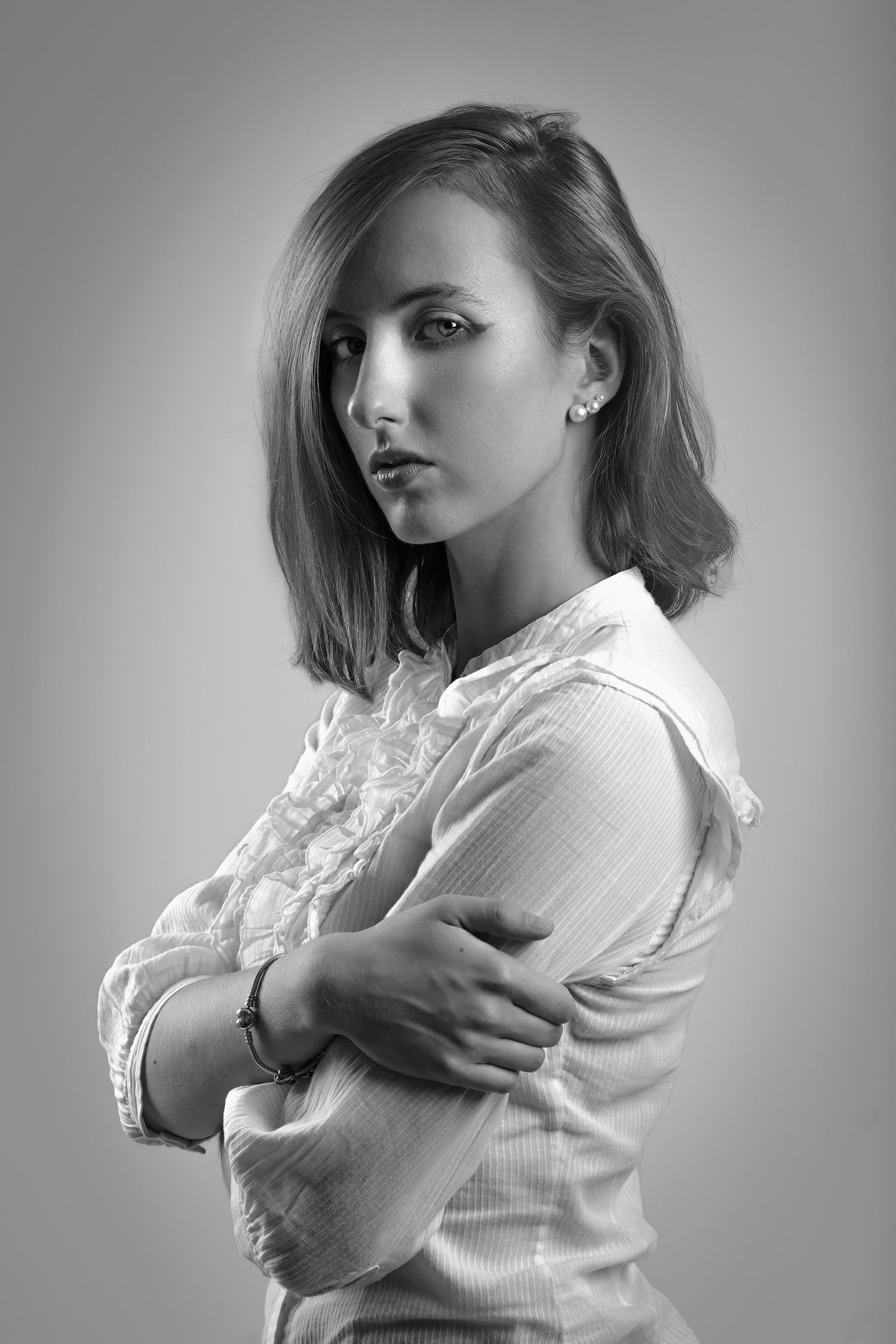 Professional fashion photographer portrait, black and white: close-up with soft studio lighting, white ruffled shirt, classic look.