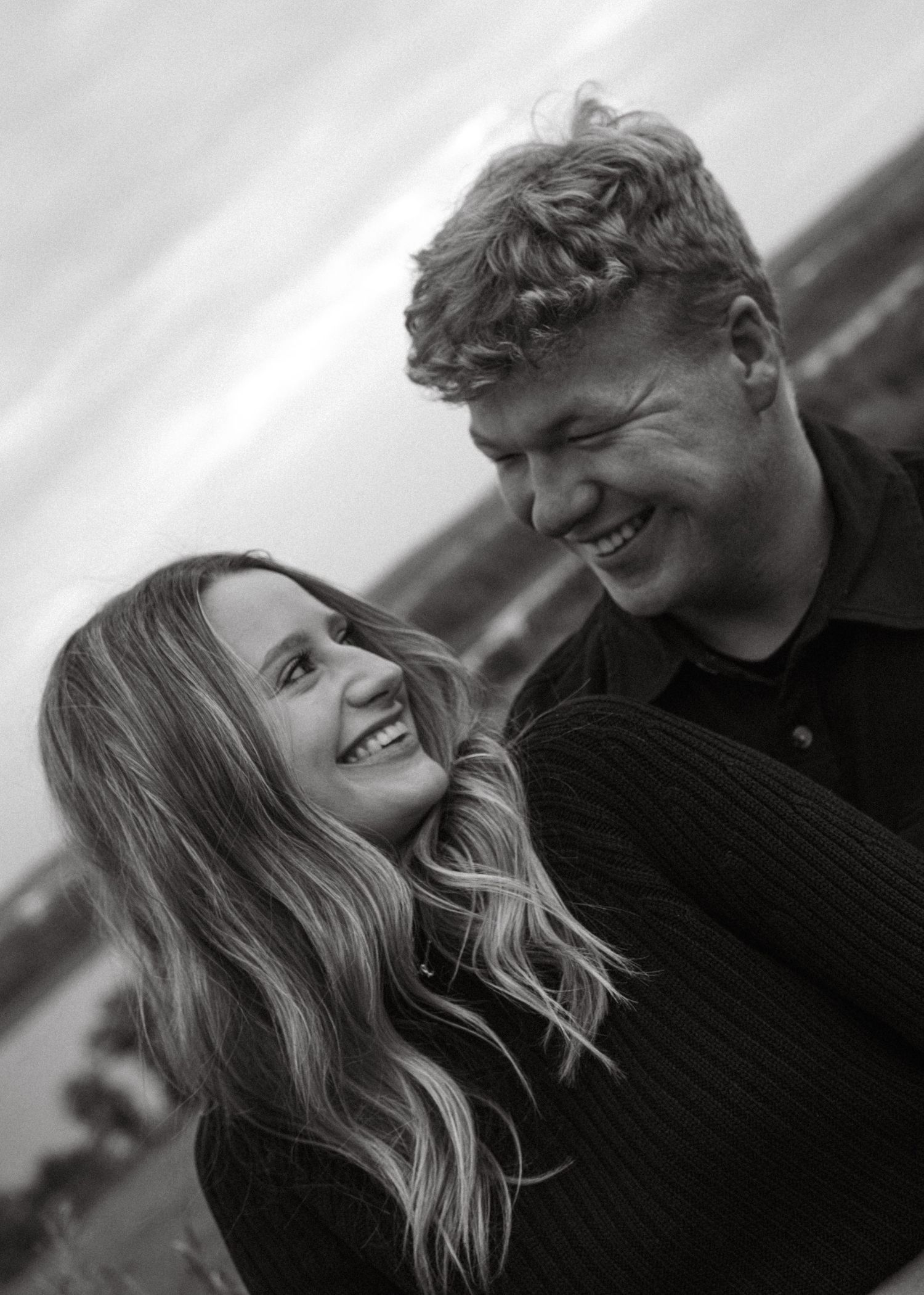 A couple shares intimate moments on a hillside in dramatic black and white photography.