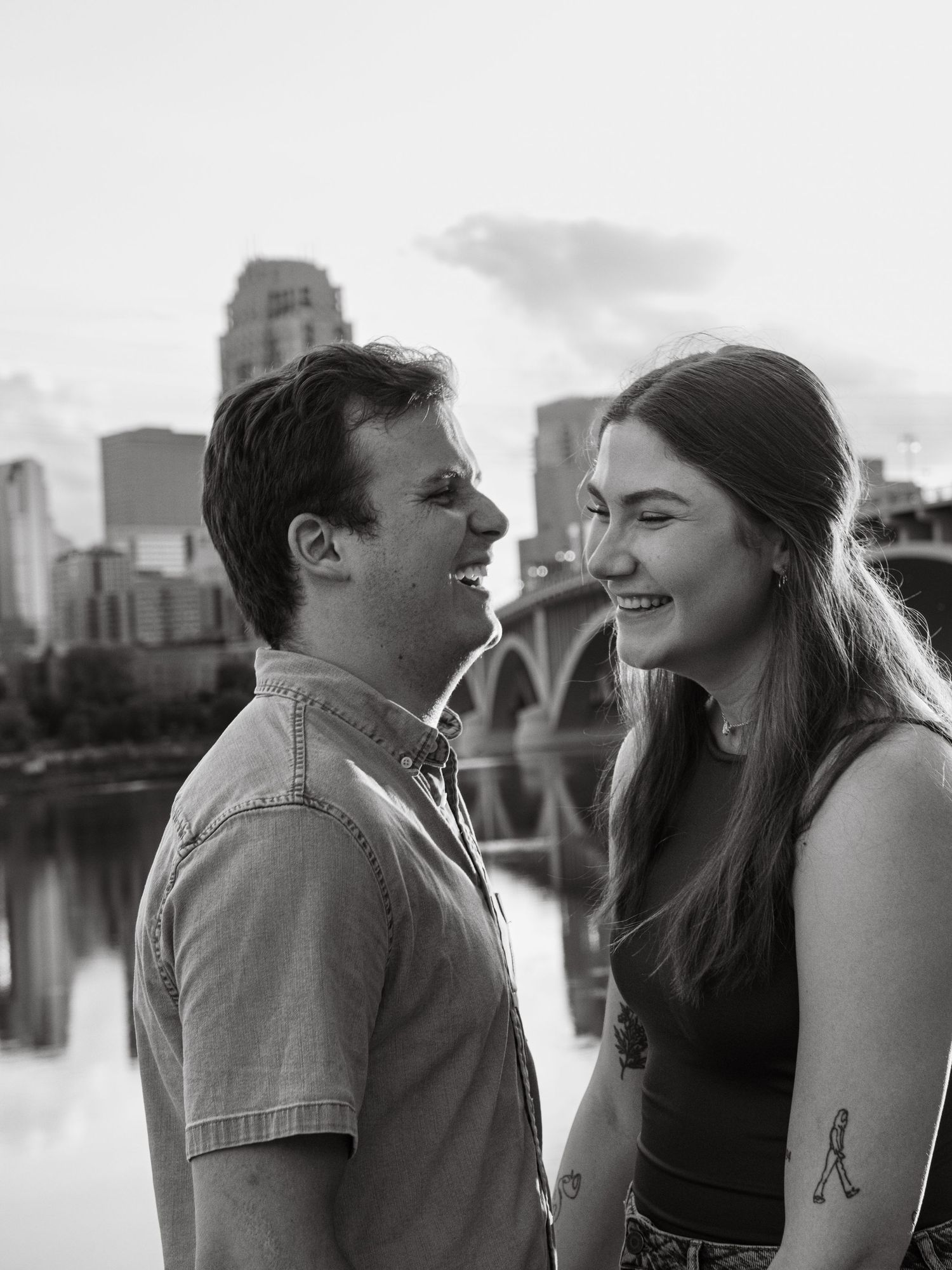 Couple sharing joyful moments by the waterfront with city skyline in background.