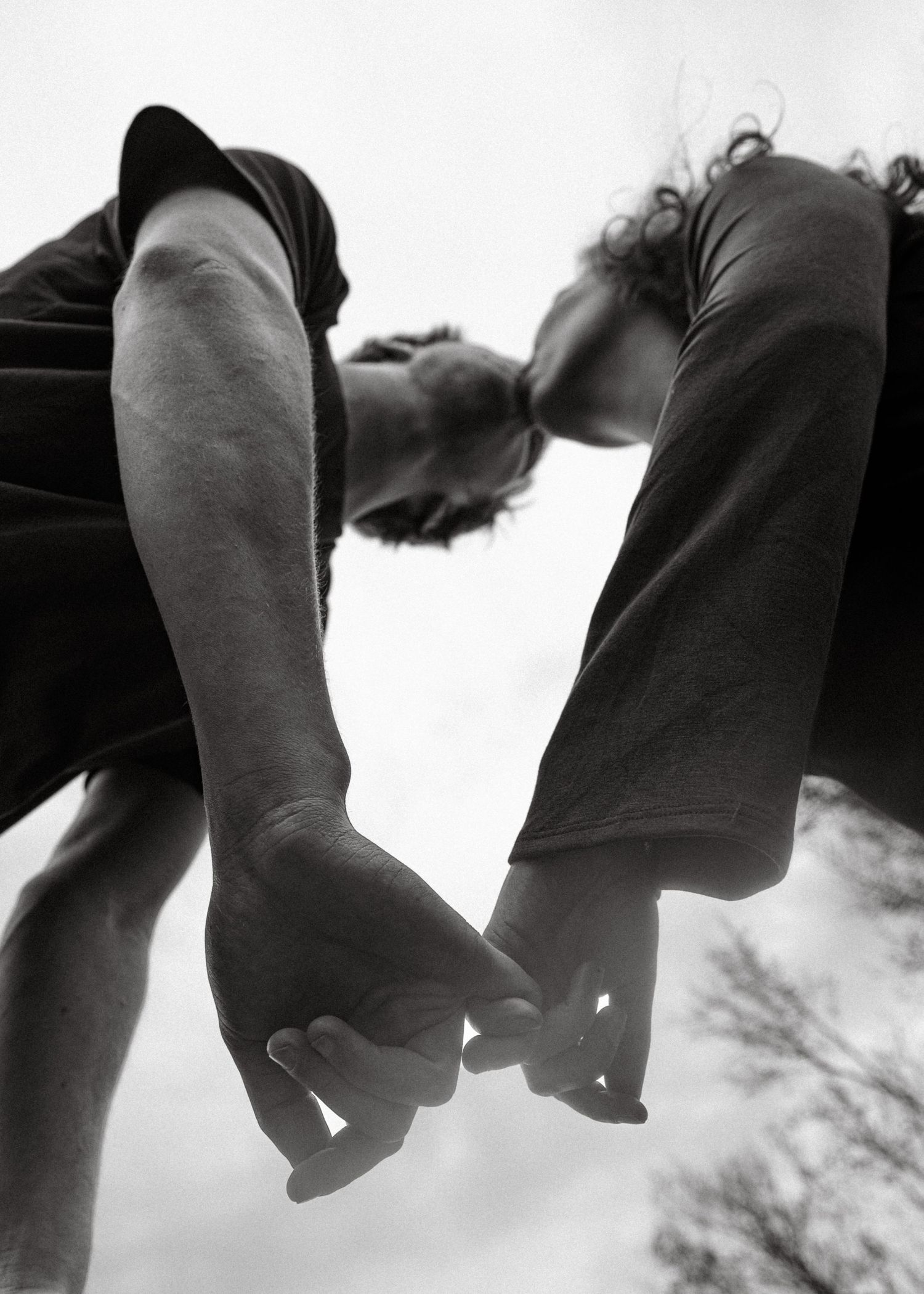 Black and white photo of two people holding hands from below, symbolizing connection and togetherness.