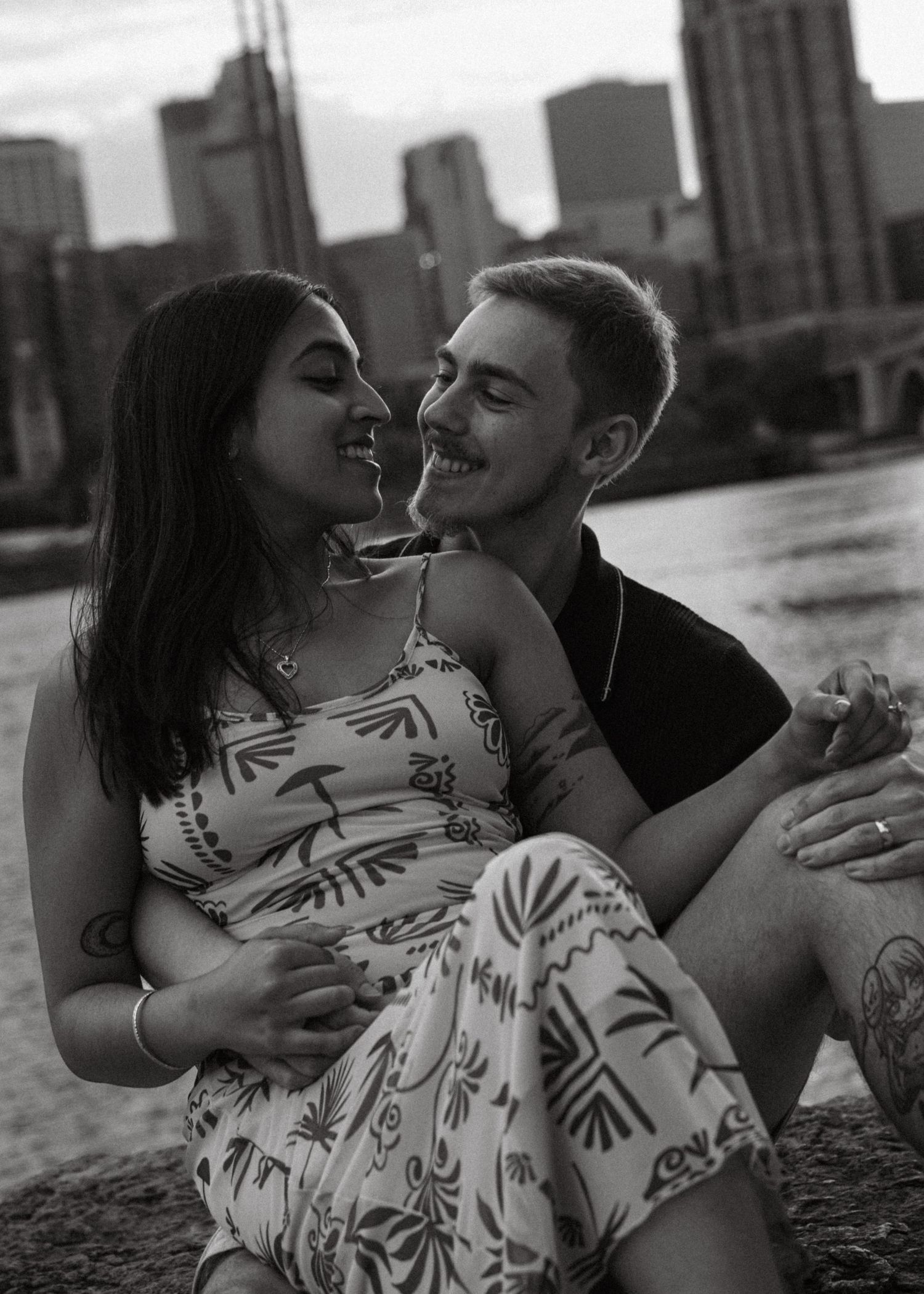 Couple sharing intimate moments by the waterfront in black and white.