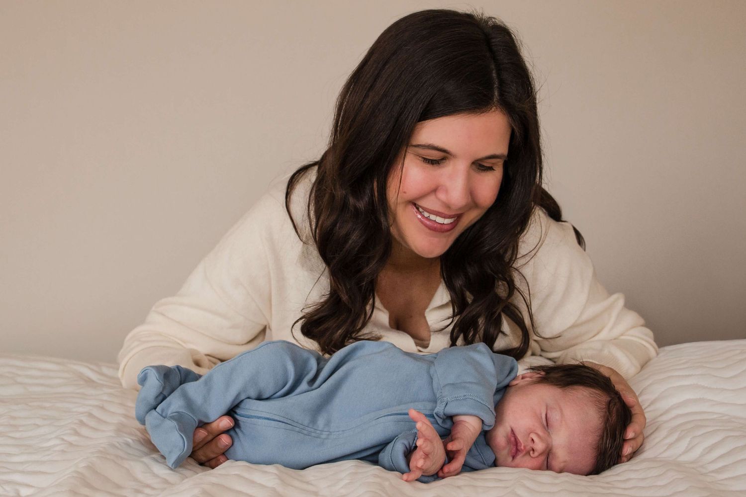 Loving mother watching over her newborn during a lifestyle newborn photography session in Toronto.