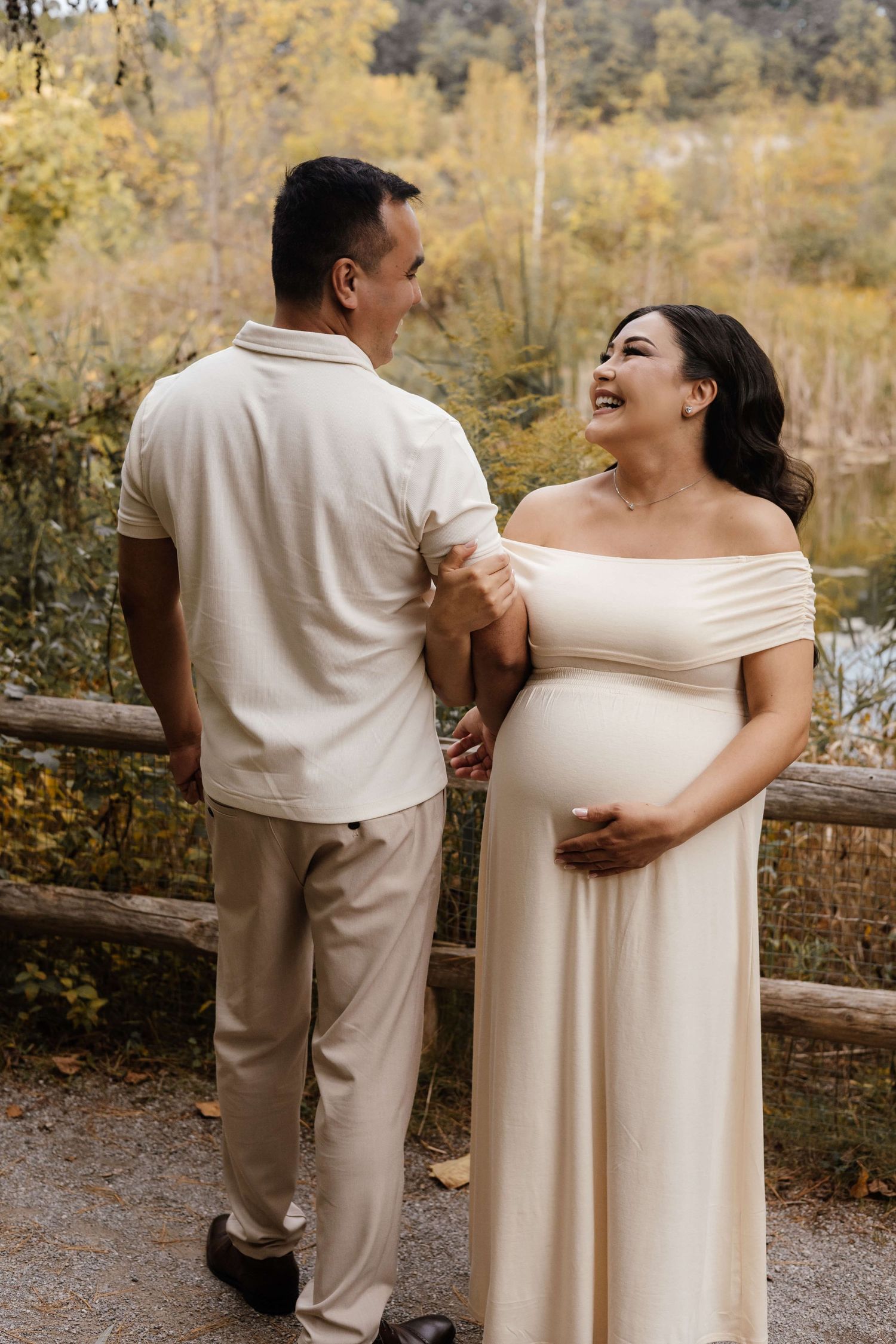 Expectant parents sharing a joyful moment at Evergreen Brick Works during an outdoor maternity photography session in Toronto.