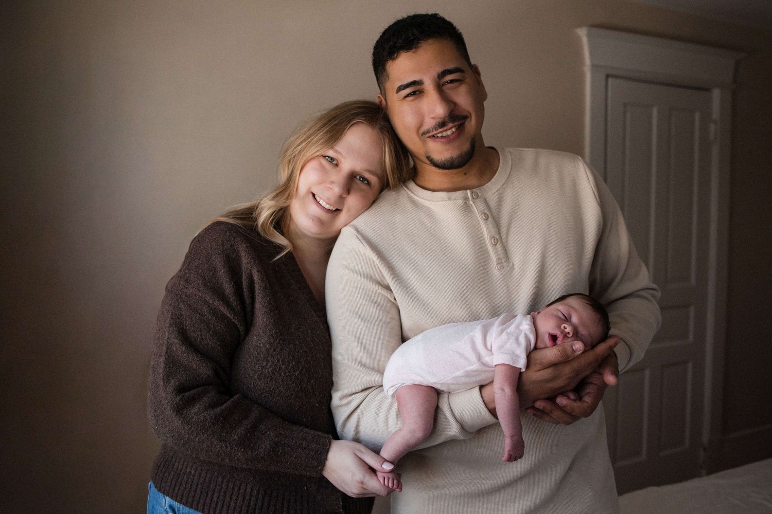 Parents holding their newborn during an in-home newborn photography session in Toronto, capturing love, connection, and family.