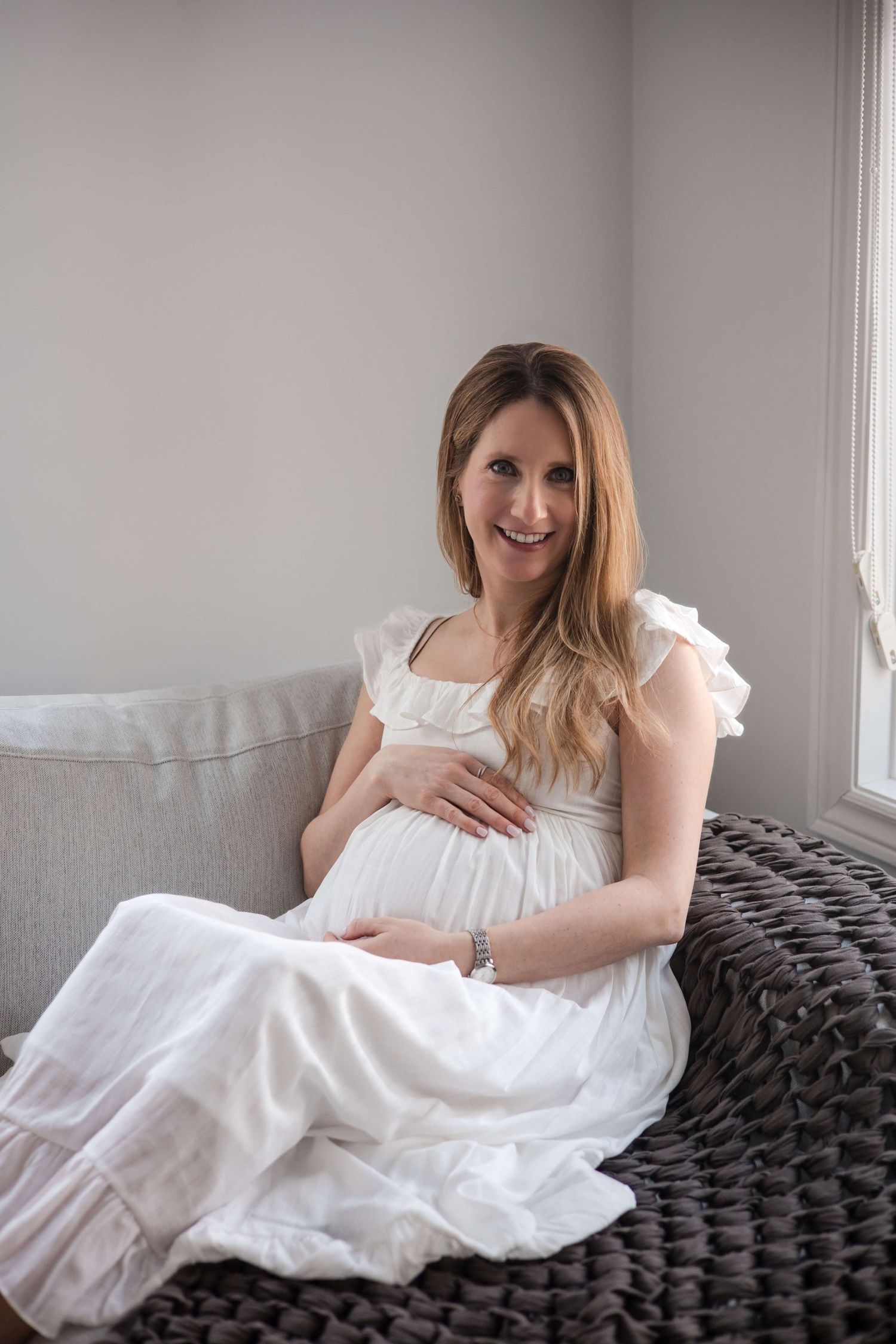 Expectant mother embracing her baby bump during an in-home maternity photography session in Toronto, capturing motherhood and anticipation.