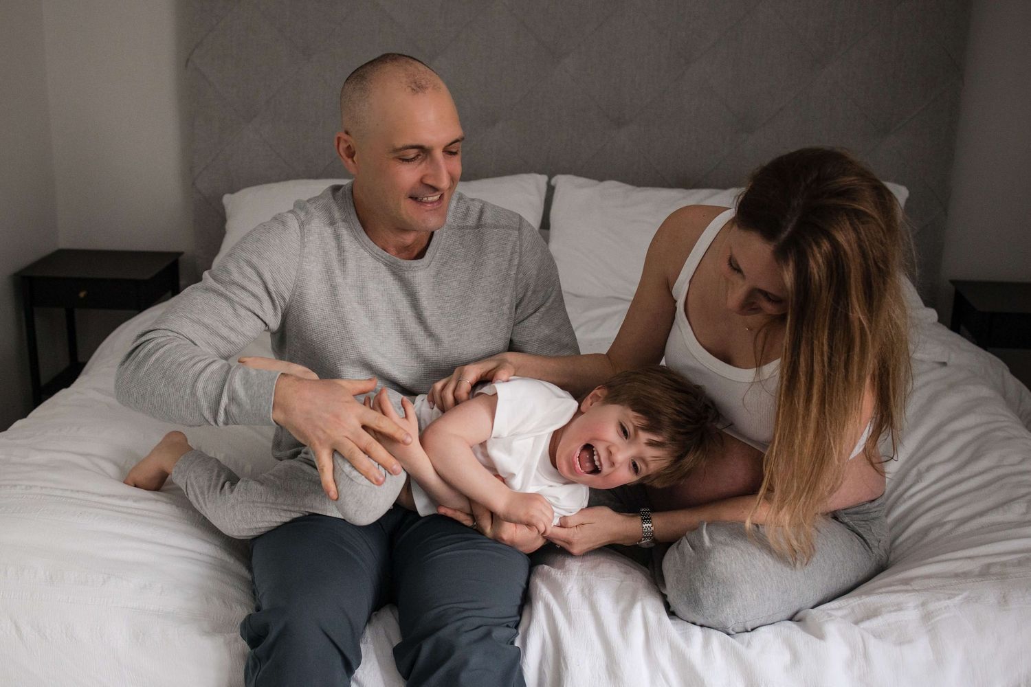 Expectant parents playing with their child during an in-home maternity photography session in Toronto, celebrating a growing family.