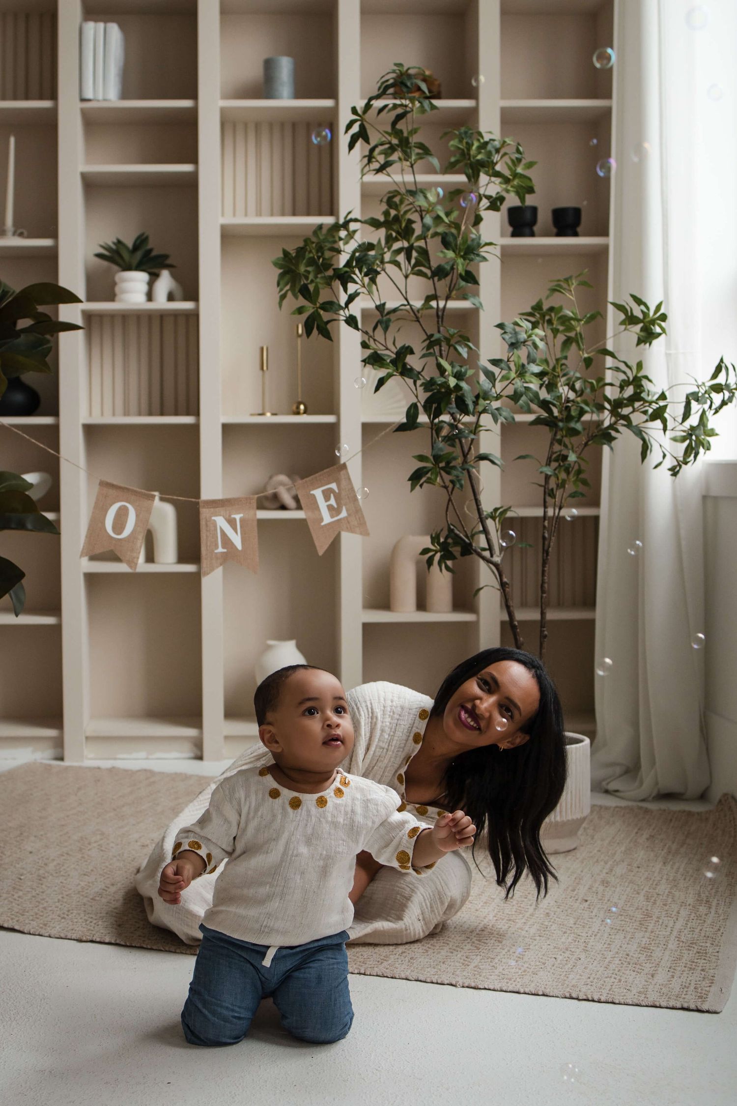 Mother and one-year-old playing together during a cake smash session at Mint Room Studios Toronto with bubbles and timeless decor.