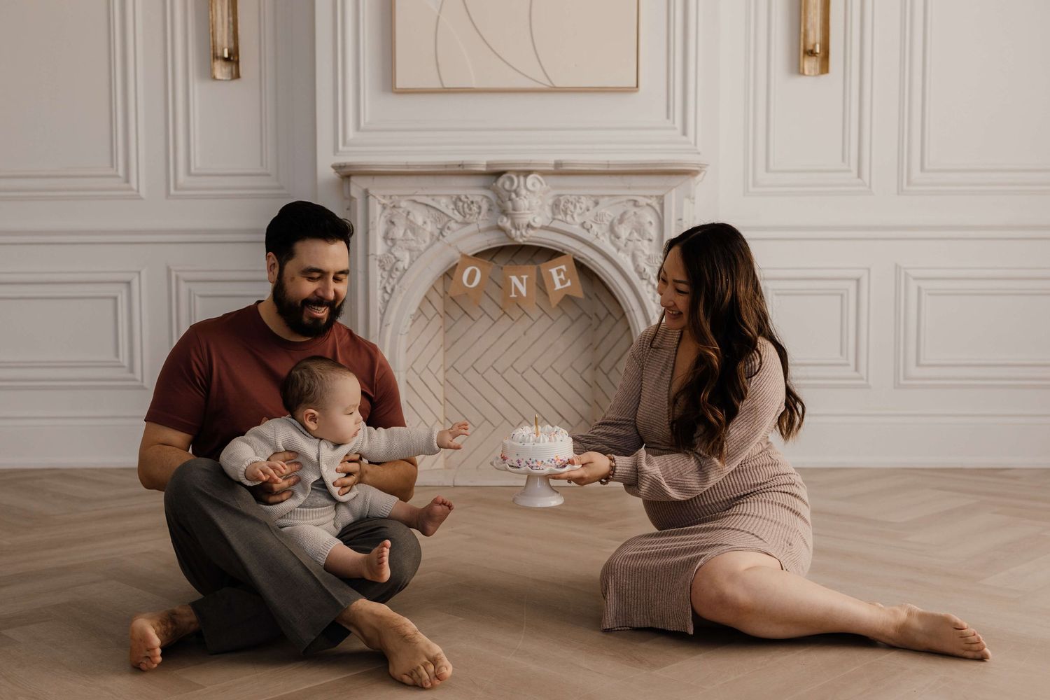 Parents and baby sharing a sweet first birthday moment during a cake smash session at Mint Room Studios in Toronto.
