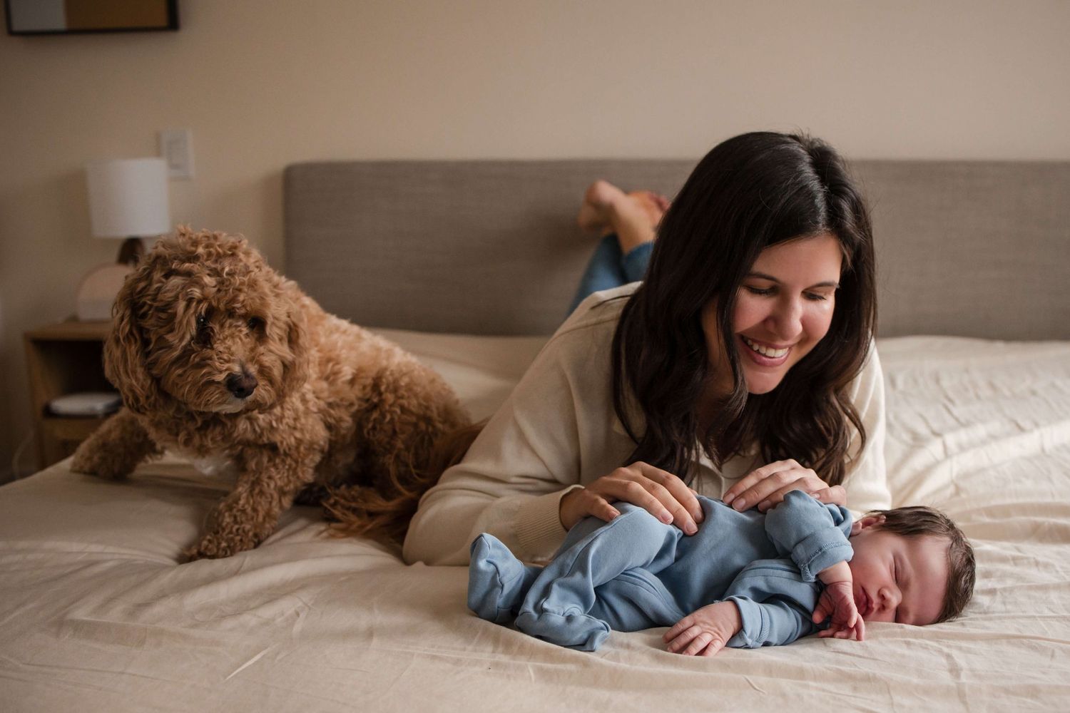 Newborn cuddles with mom while the family dog joins the moment during a Toronto newborn session.