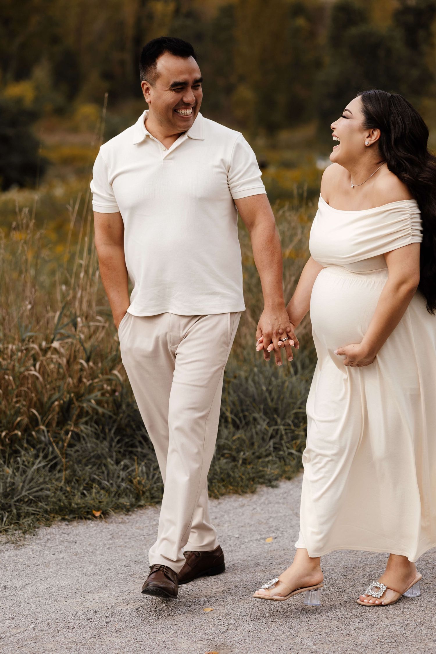 Expectant parents holding hands at Evergreen Brick Works during an outdoor maternity photography session in Toronto, capturing love.