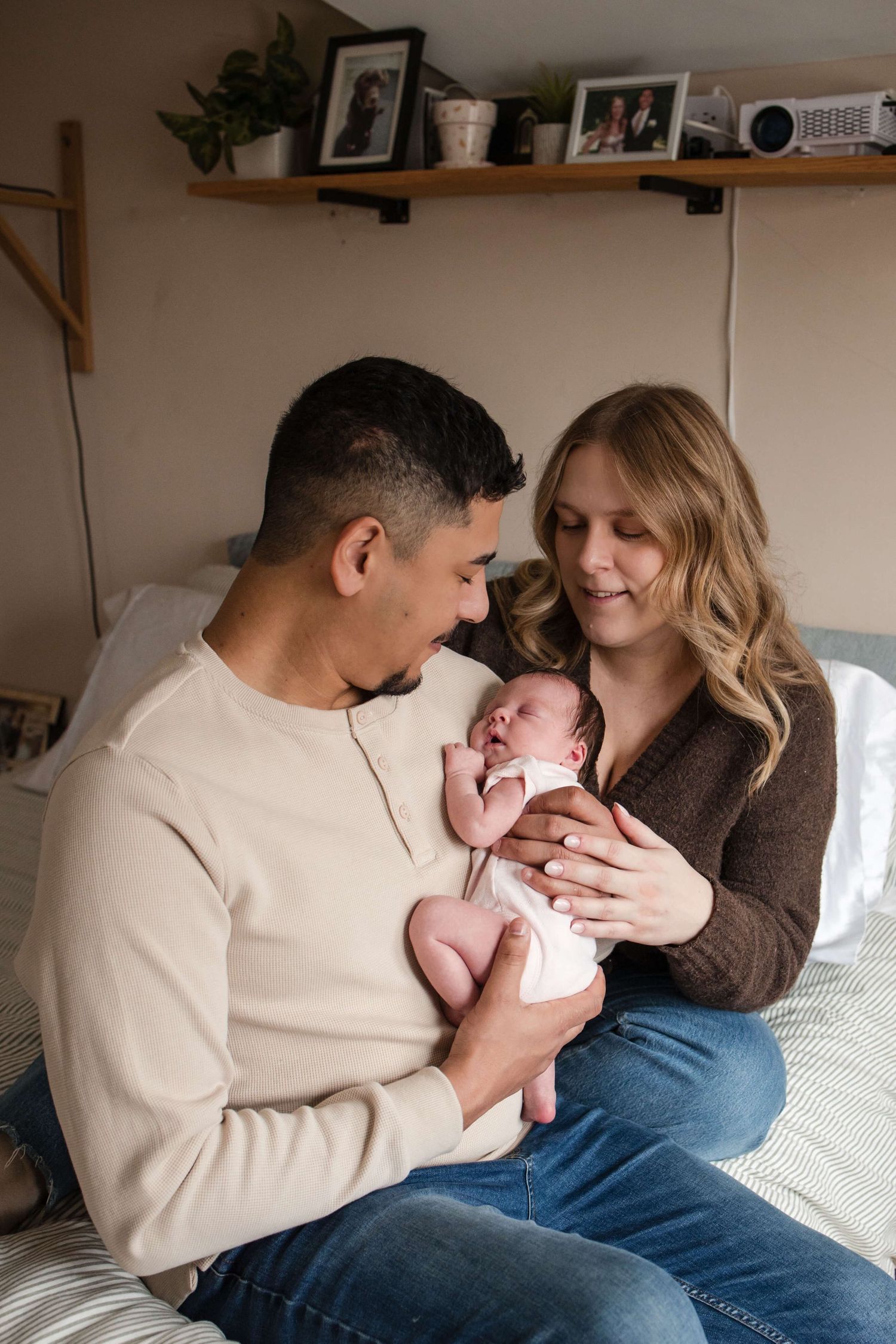 Parents cuddling their newborn during an in-home newborn photography session in Toronto, capturing love, connection, and family.