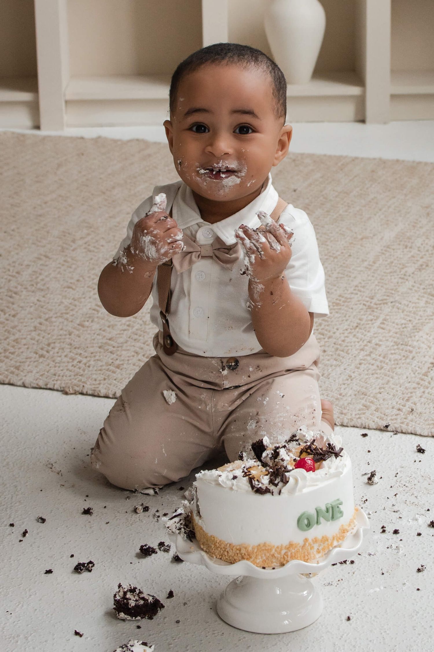 One-year-old enjoying a cake smash session at Mint Room Studios in Toronto with a neutral setup, timeless decor, and natural style.