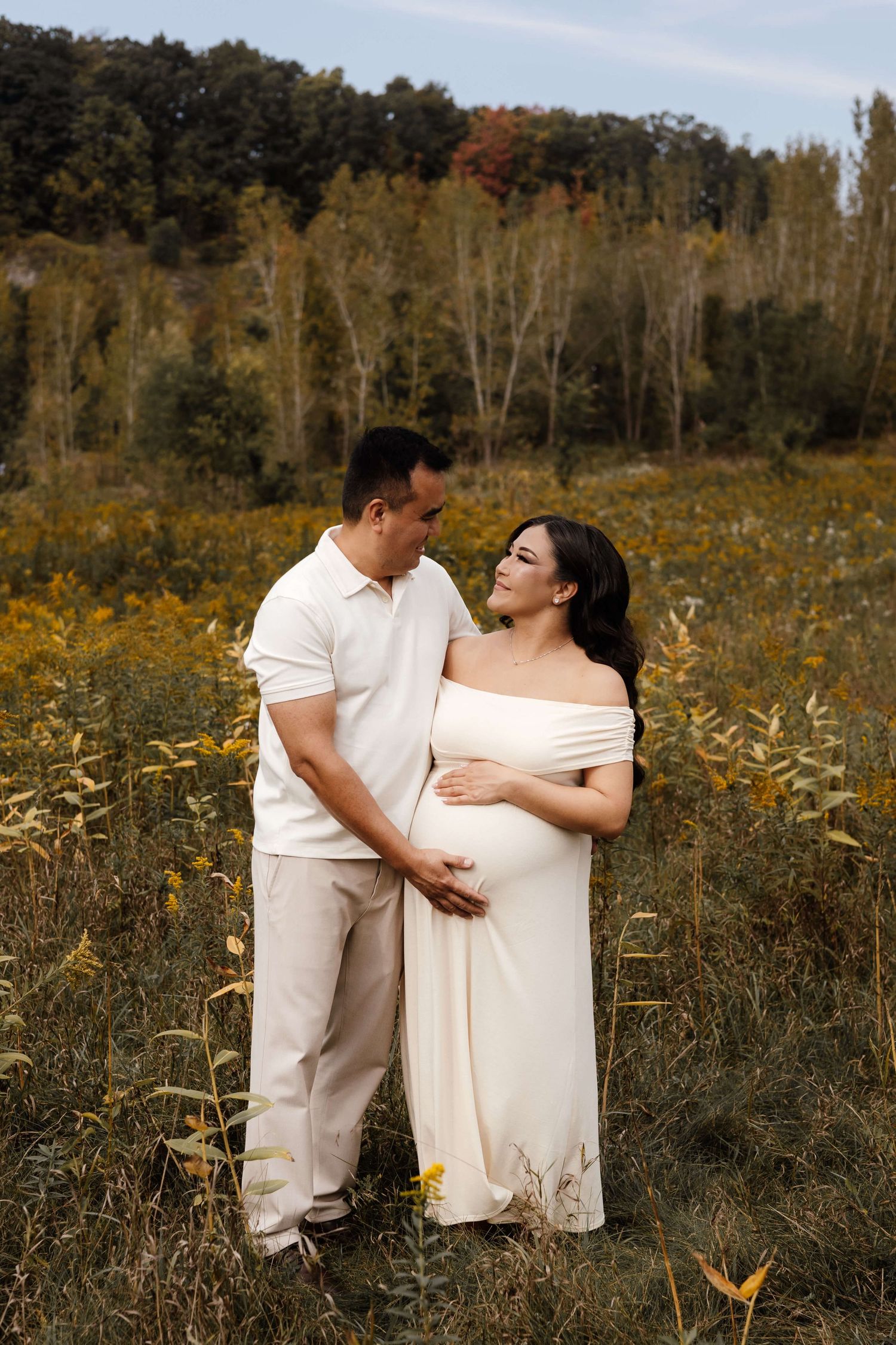 Expectant parents sharing a joyful moment at Evergreen Brick Works during an outdoor maternity photography session in Toronto.