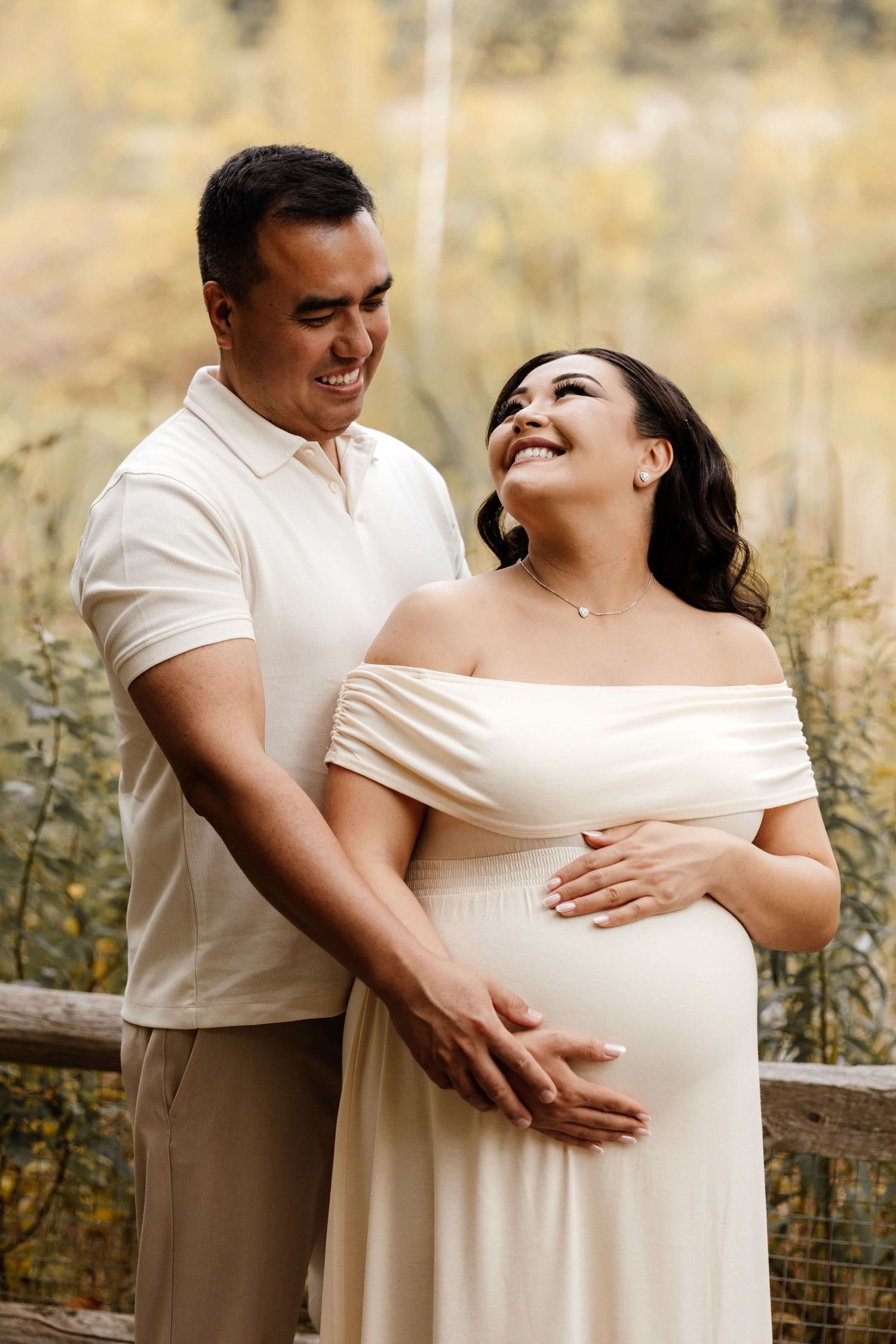 Expectant parents sharing a joyful moment at Evergreen Brick Works during an outdoor maternity photography session in Toronto.